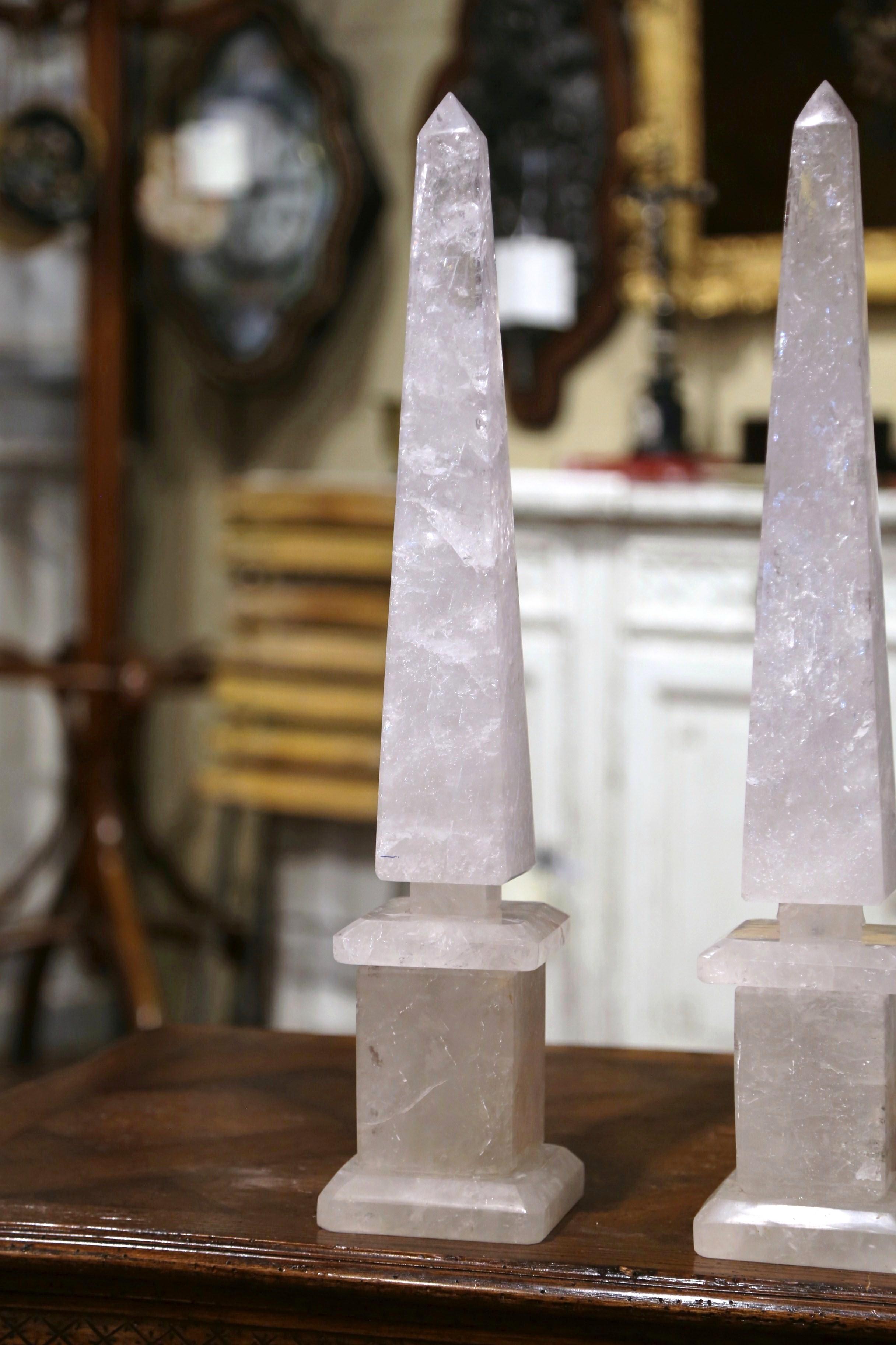 Crafted in Brazil and made of rock crystal, each obelisk is raised on a stepped square base and features exquisite craftsmanship with a tapered and pointed stem. Both elegant pieces are in excellent condition. Display these tall obelisks on a