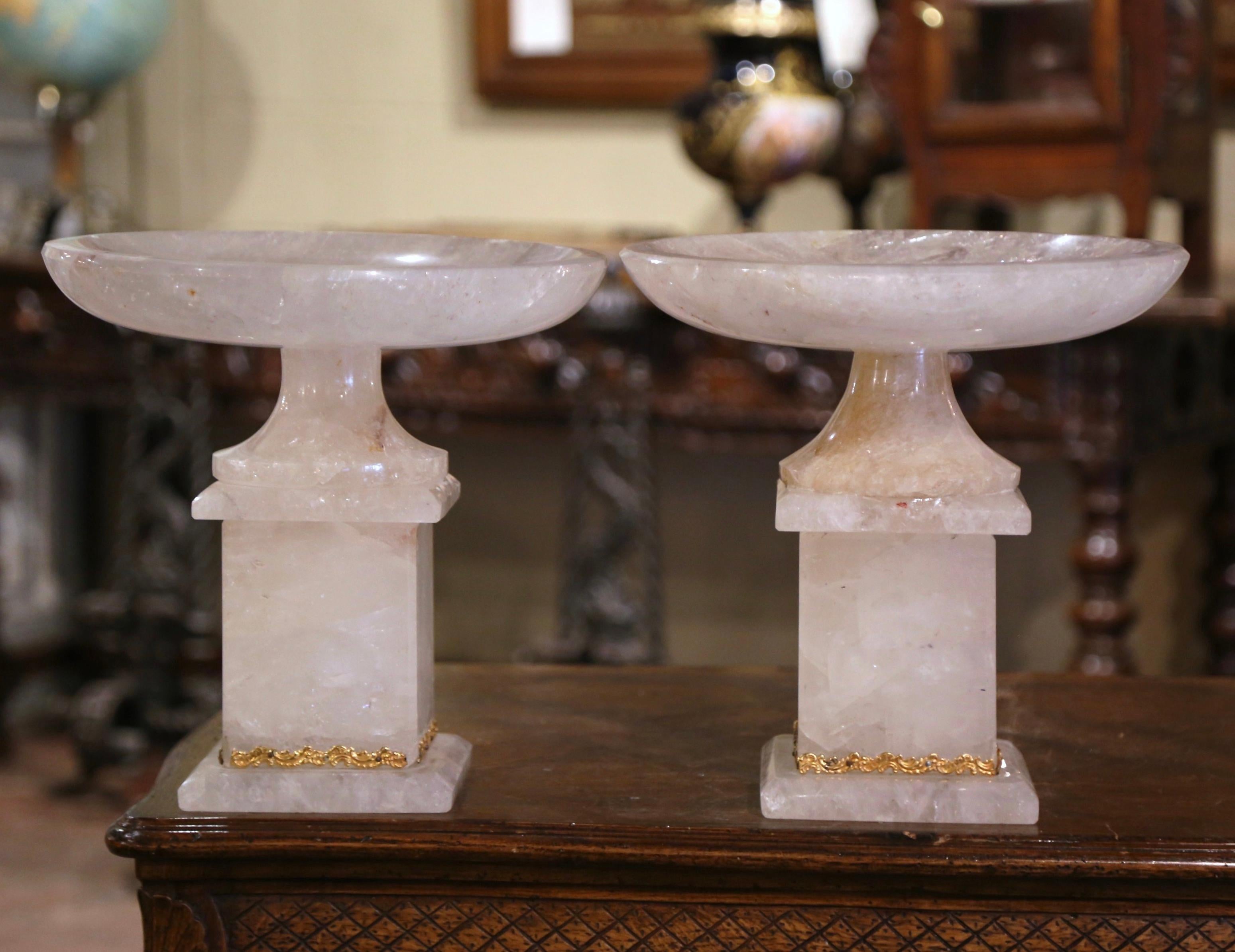 Diese bedeutenden handgeschnitzten Bergkristallschalen mit Ständer wurden in Brasilien hergestellt. Die zweiteilige Kompottschale steht auf einem quadratischen Sockel, der mit einem Messingband verziert ist, und einer runden, drehbaren Schale. Das