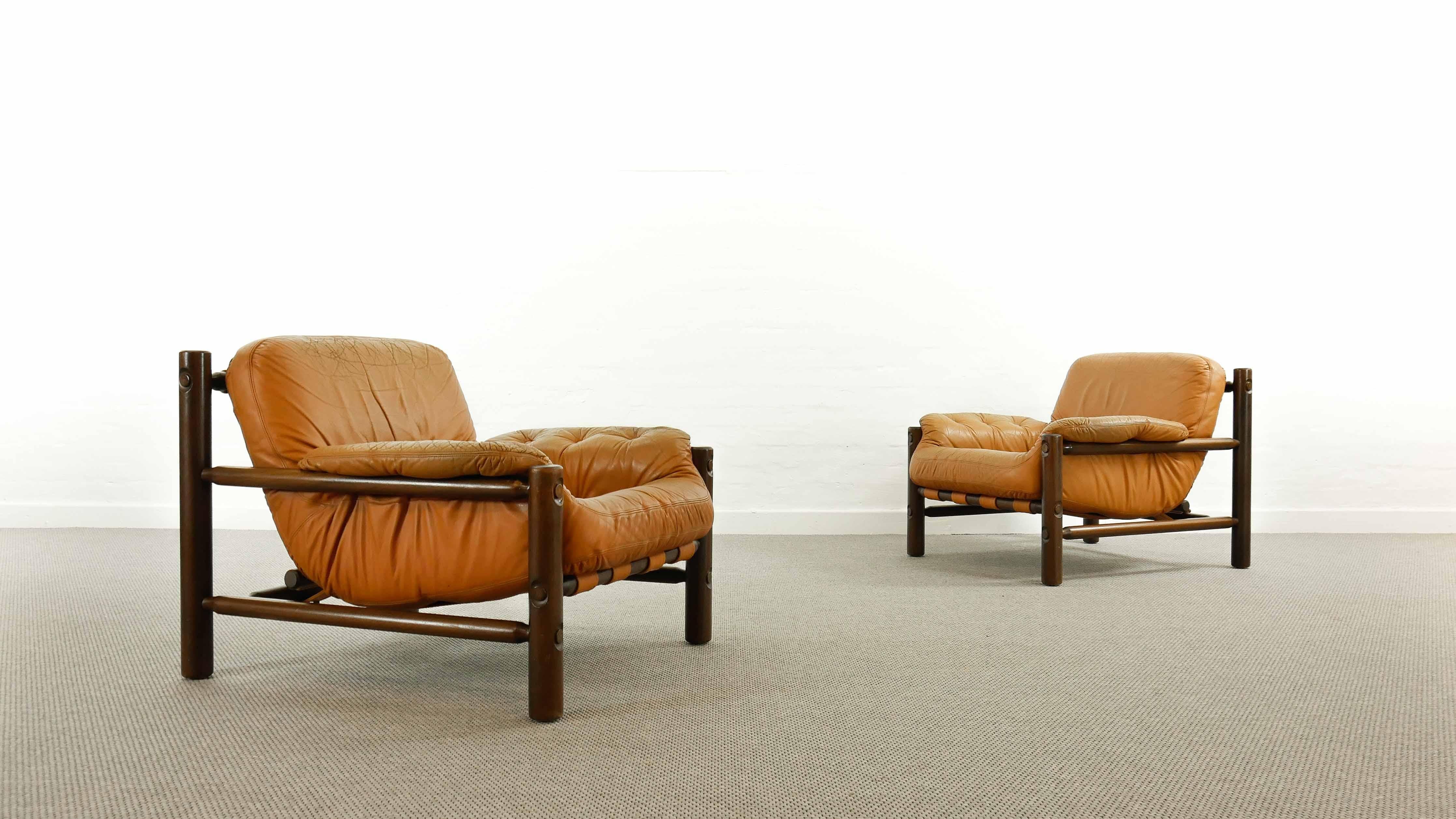 Beautiful pair of lounge chairs Brazilian style from the late 1960s-early 1970s.Cognac colored leather with a beautiful patina. Very elegant and comfortable armchairs in good vintage condition. Buttoned leather upholstery mounted by belts and belt