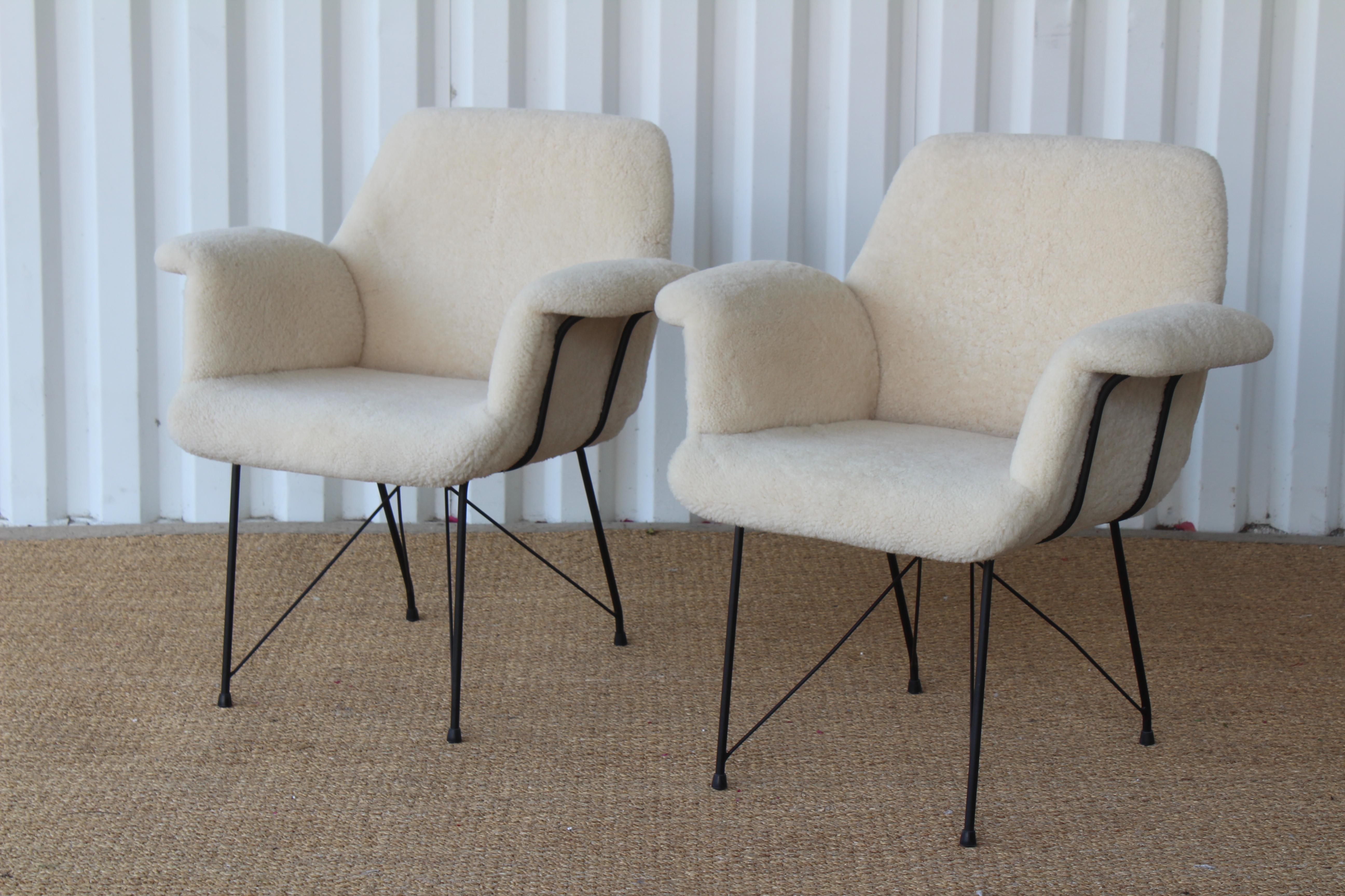 Rare pair of armchairs designed by Carlo Hauner and Martin Eisler for Forma, Brazil, 1955. The pair have been completely restored with new sheep hide upholstery. The solid iron bases have been powder coated back the original black finish. New rubber