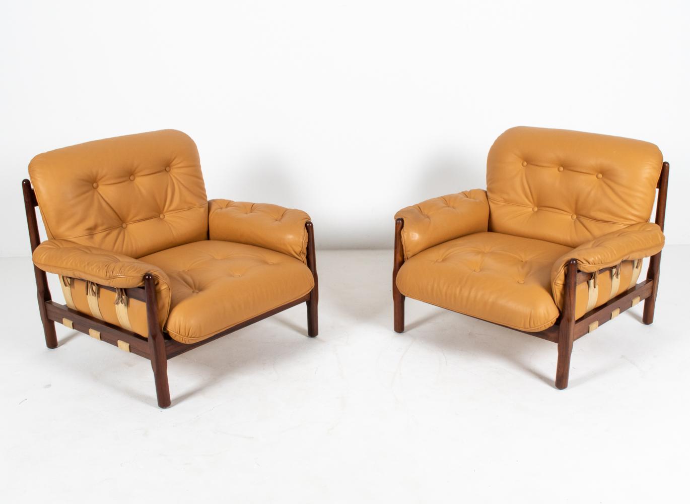 Generous proportions and luxurious finishes set this fabulous pair of Brazilian Modernist lounge chairs apart from the rest. The frames are crafted from gorgeous solid rosewood, with interesting sculptural chamfering at the legs. The tufted cushions