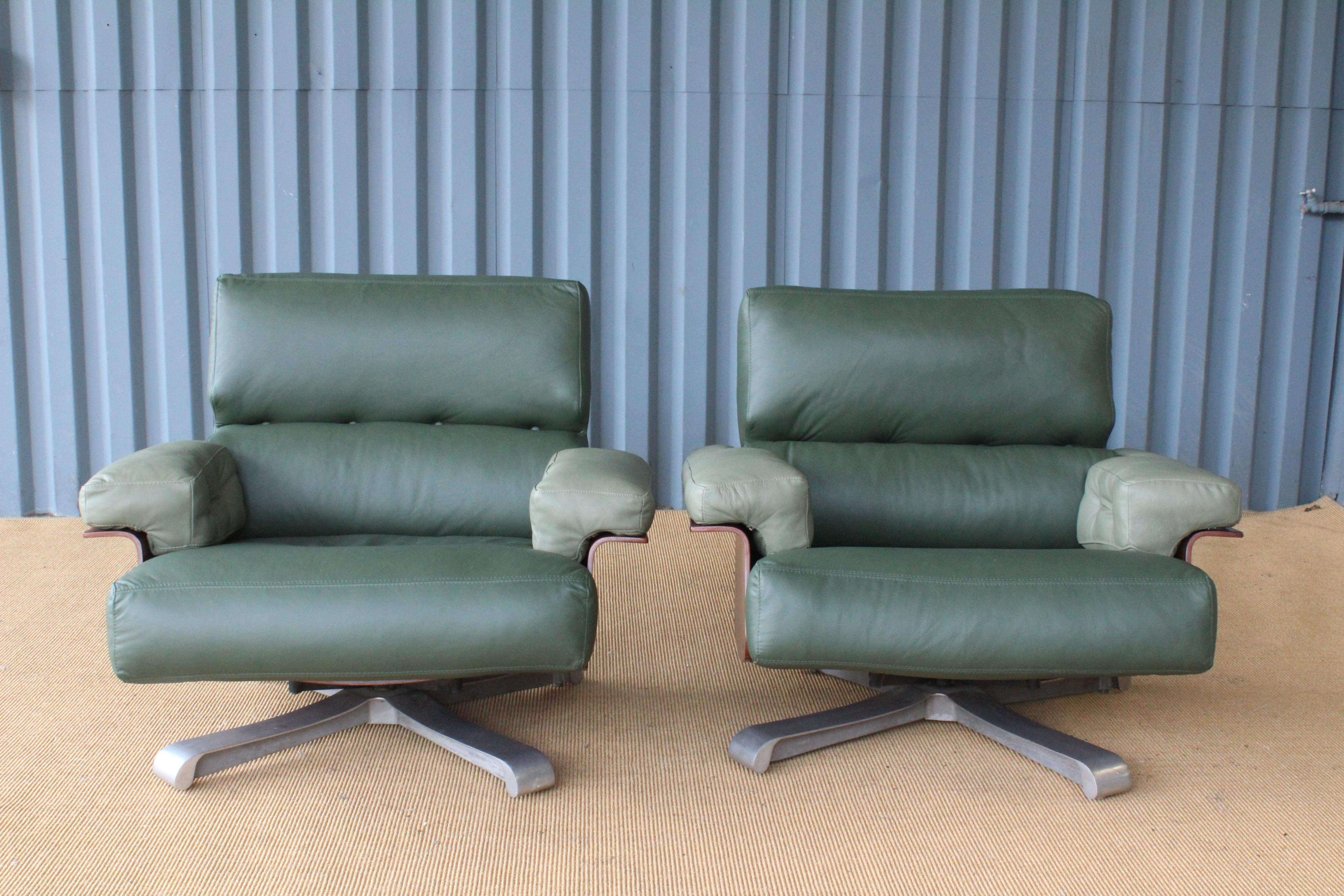 Pair of swiveling armchairs in Brazilian rosewood. The pair sits on swiveling aluminum bases and feature new cushions in green leather.