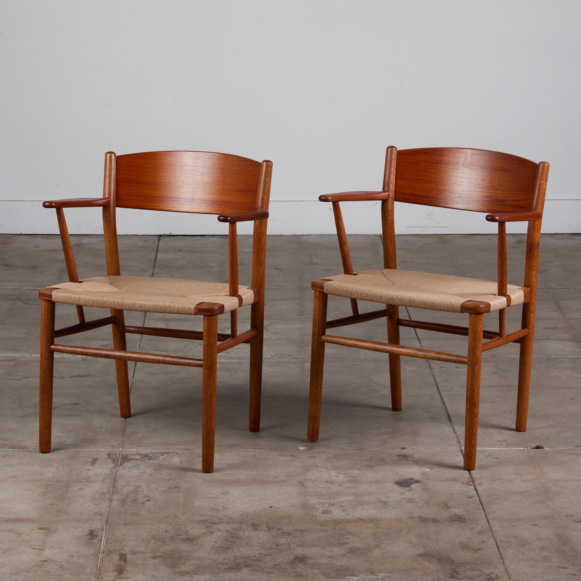 A pair of Børge Mogensen arm chairs, Denmark, c.1950s, feature hand woven Danish paper cord seats. The chair backs made of teak, while the legs and frame are made of oak, creating a slight color contrast. 

Dimensions: 23