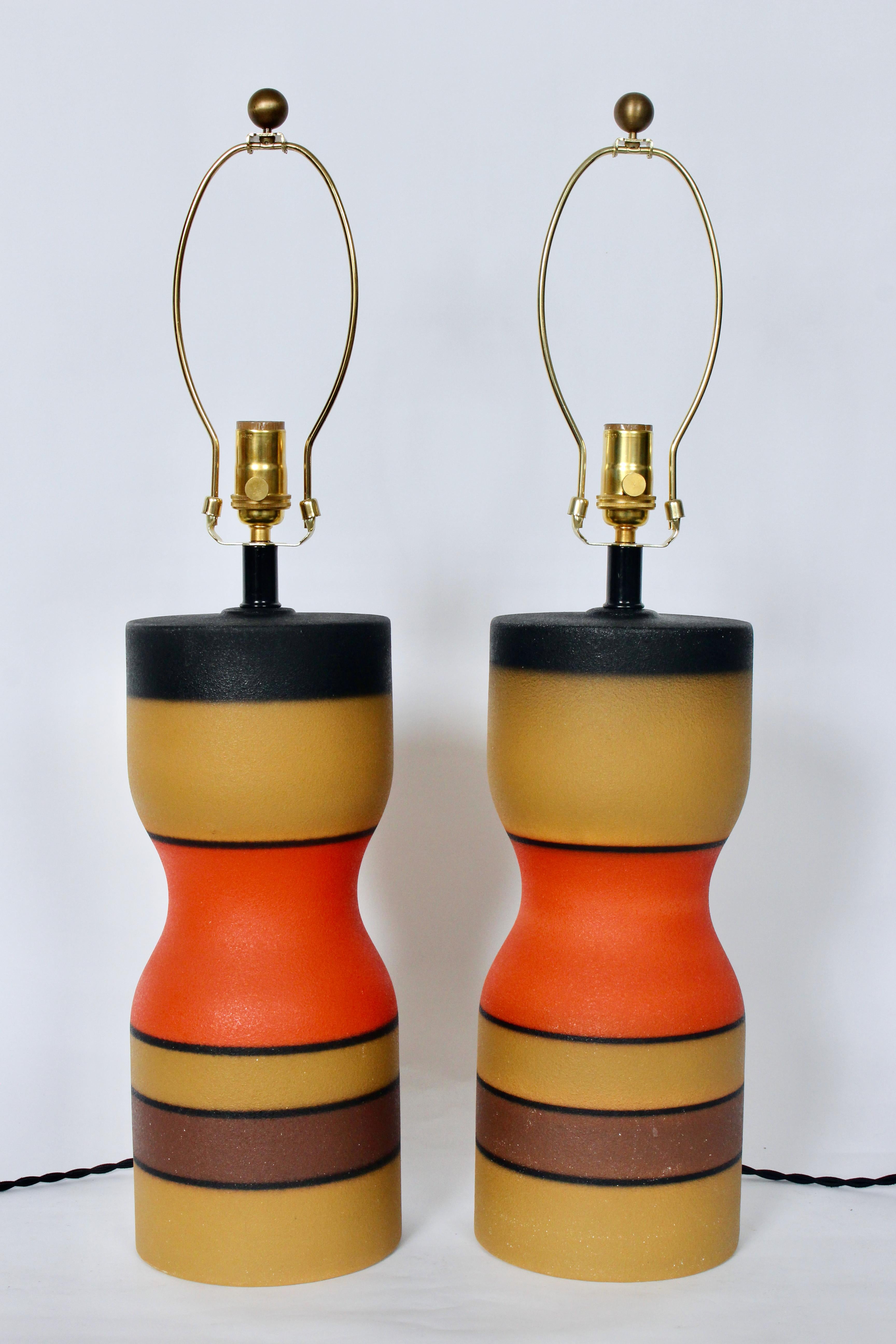 Pair of Bruno Gambone style multi color block stripe table lamps, circa 1970. Featuring a matte glazed smoothly textured corseted form (5D) layered with three Mustard fields, a singular brown band, red orange waists, black color fields to top, thin