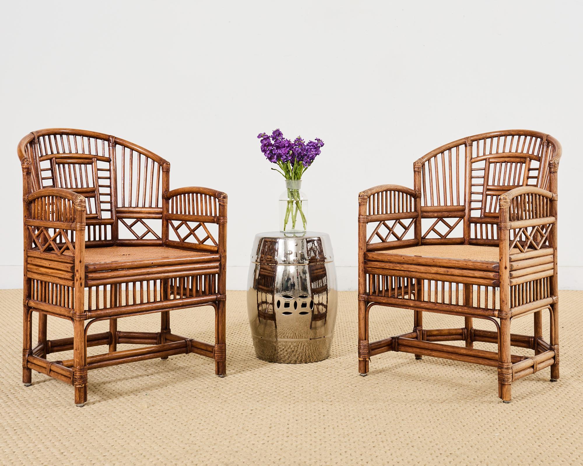 Stylish pair of bamboo rattan dining armchairs made in the English Brighton Pavilion style. The chairs feature Chinese Chippendale style open fretwork designs hand-crafted from bent rattan poles. The rattan has a desirable warm, dark honey-toned