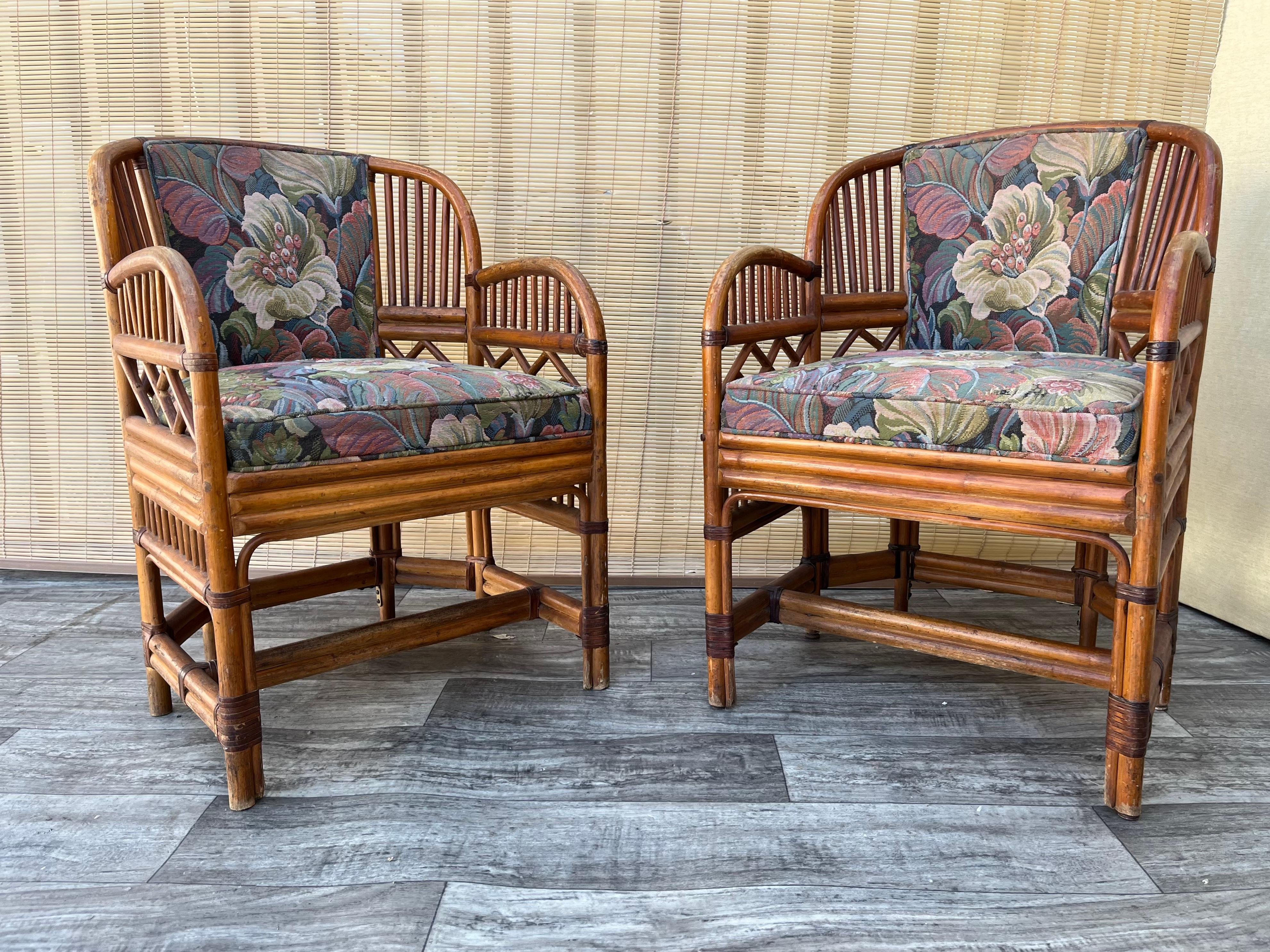 A Pair of Vintage Midcentury Chinoiserie Brighton Pavillion Style Upholstered Rattan Armchairs. Circa 1960s,
Features a rattan frame with leather straps and upholstered seat cushions and backrests.  In good original structurally sound and sturdy