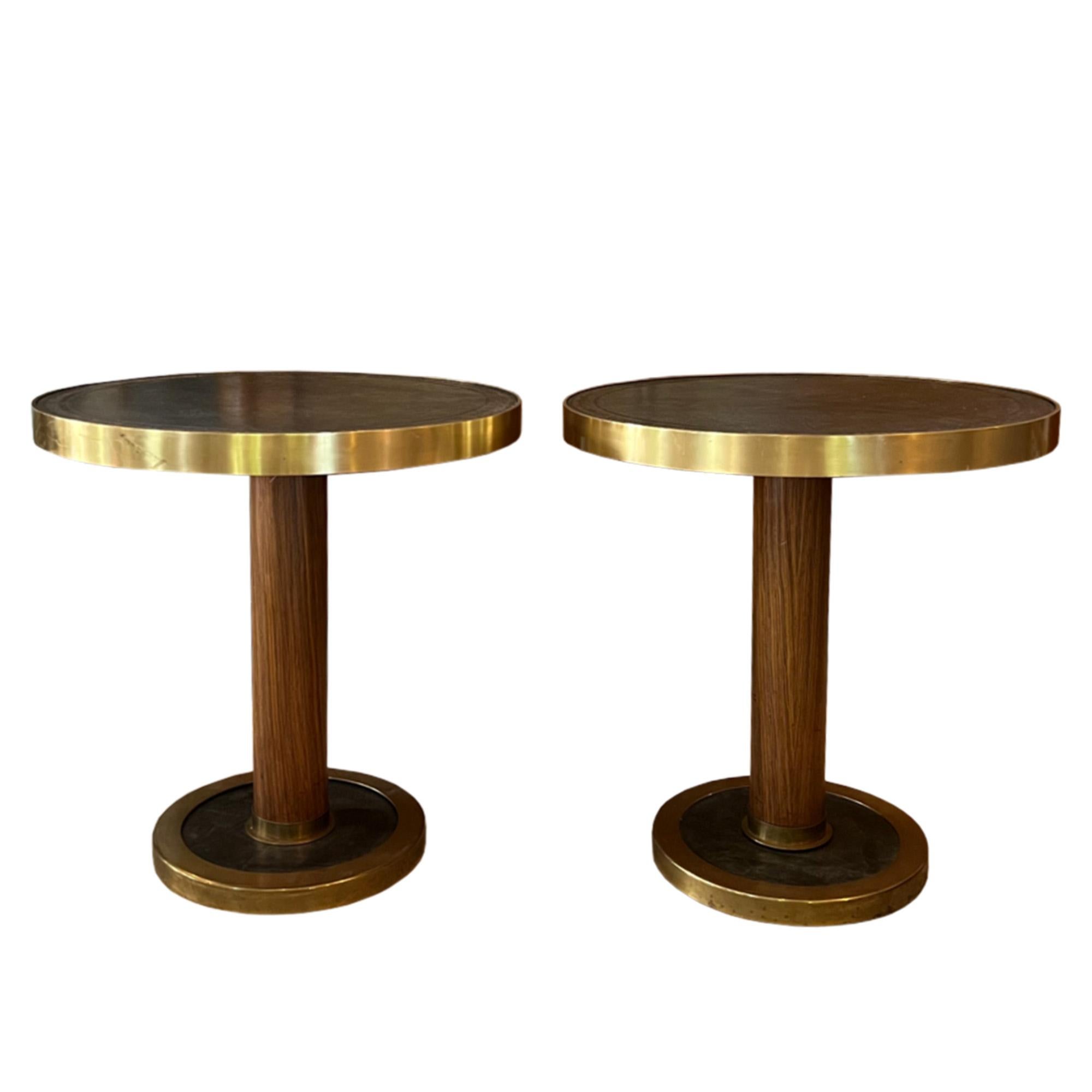 An attractive pair of side tables, designed to remain stable on board a ship. 

The brown leather tops are tooled nicely with a bronze embossed design - these are supported by wood columns and solid bases.

Finished with brass detail, these