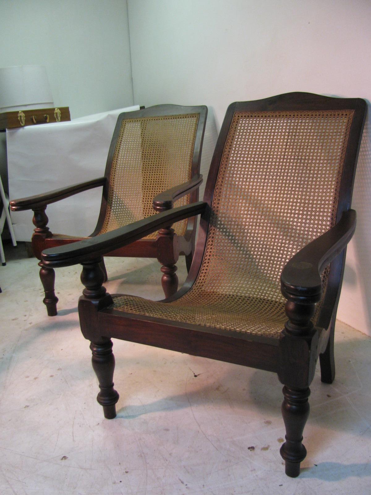 Elegante paire de chaises Plantation, chaises longues ou fauteuils, en bois dur massif et cannage, de l'époque coloniale britannique. Les chaises sont équipées d'accoudoirs pivotants. La construction est faite à la main avec des pieds tournés, une