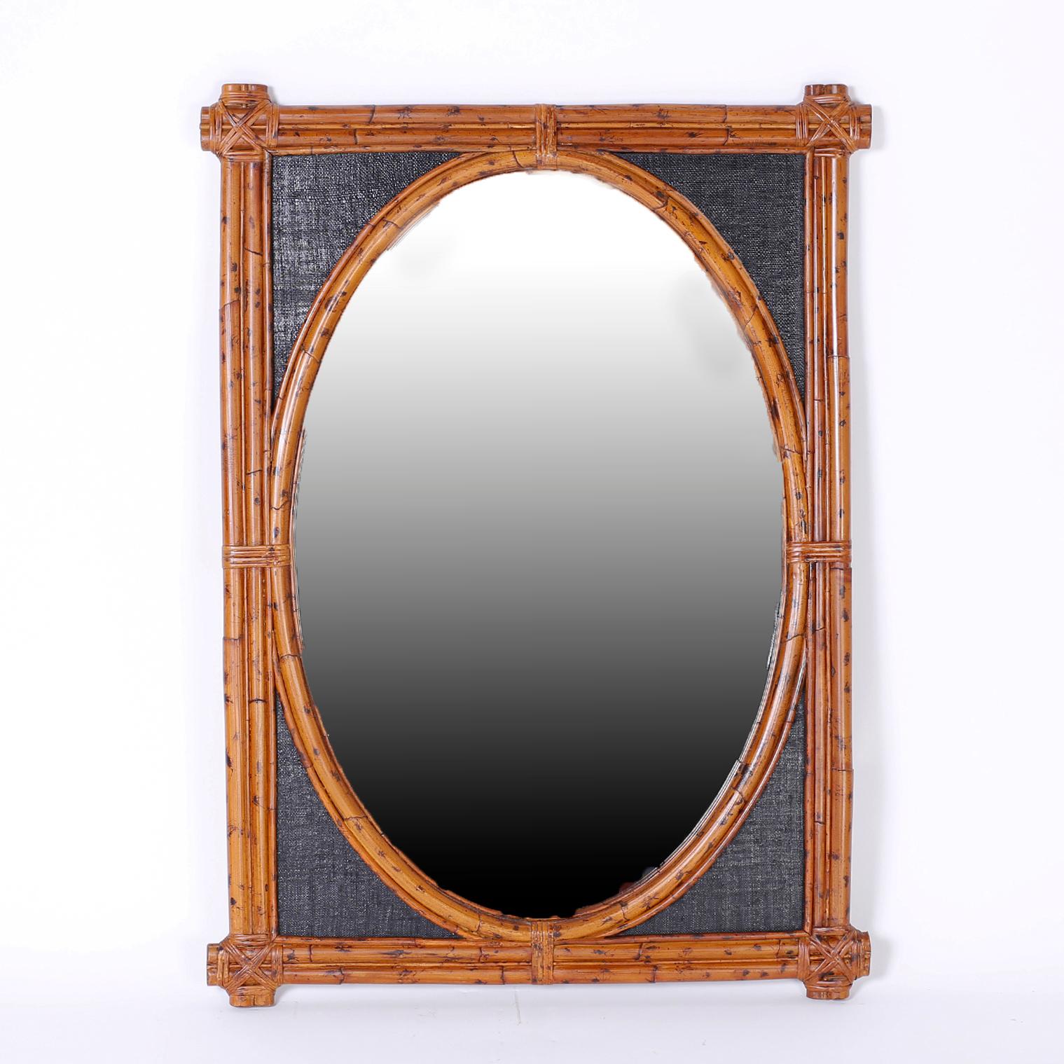 Midcentury pair of wall mirrors with a rectangular burnt bamboo frame around an oval mirror framed in bent burnt bamboo with inside panels of black painted grasscloth.