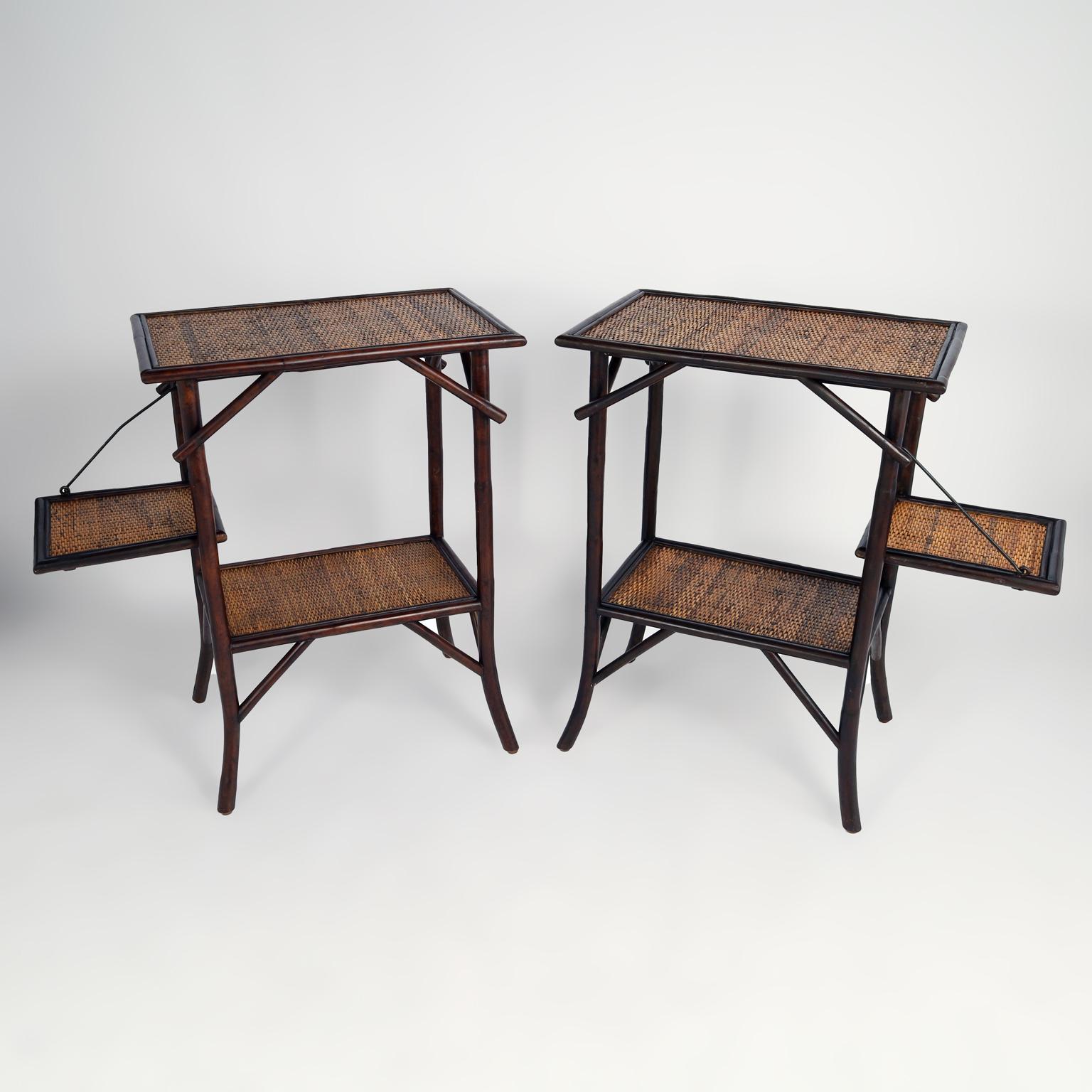 Unusual pair of mid century British colonial style stands crafted with faux bamboo frames having brackets and splayed legs featuring two tiers and an extra fold down shelf all covered in grasscloth or woven reed. 

Closed width is 24
