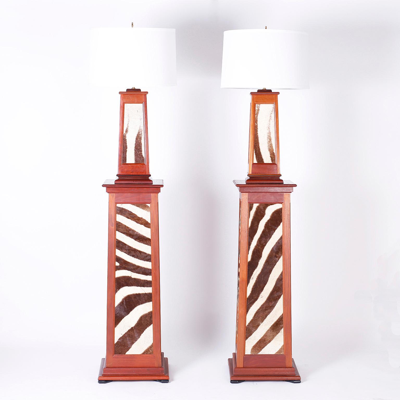 Pair of British Colonial floor lamps with a Classic tapered form custom crafted in mahogany with exotic zebra hide panels all around. Available with linen or the original lambskin shades.