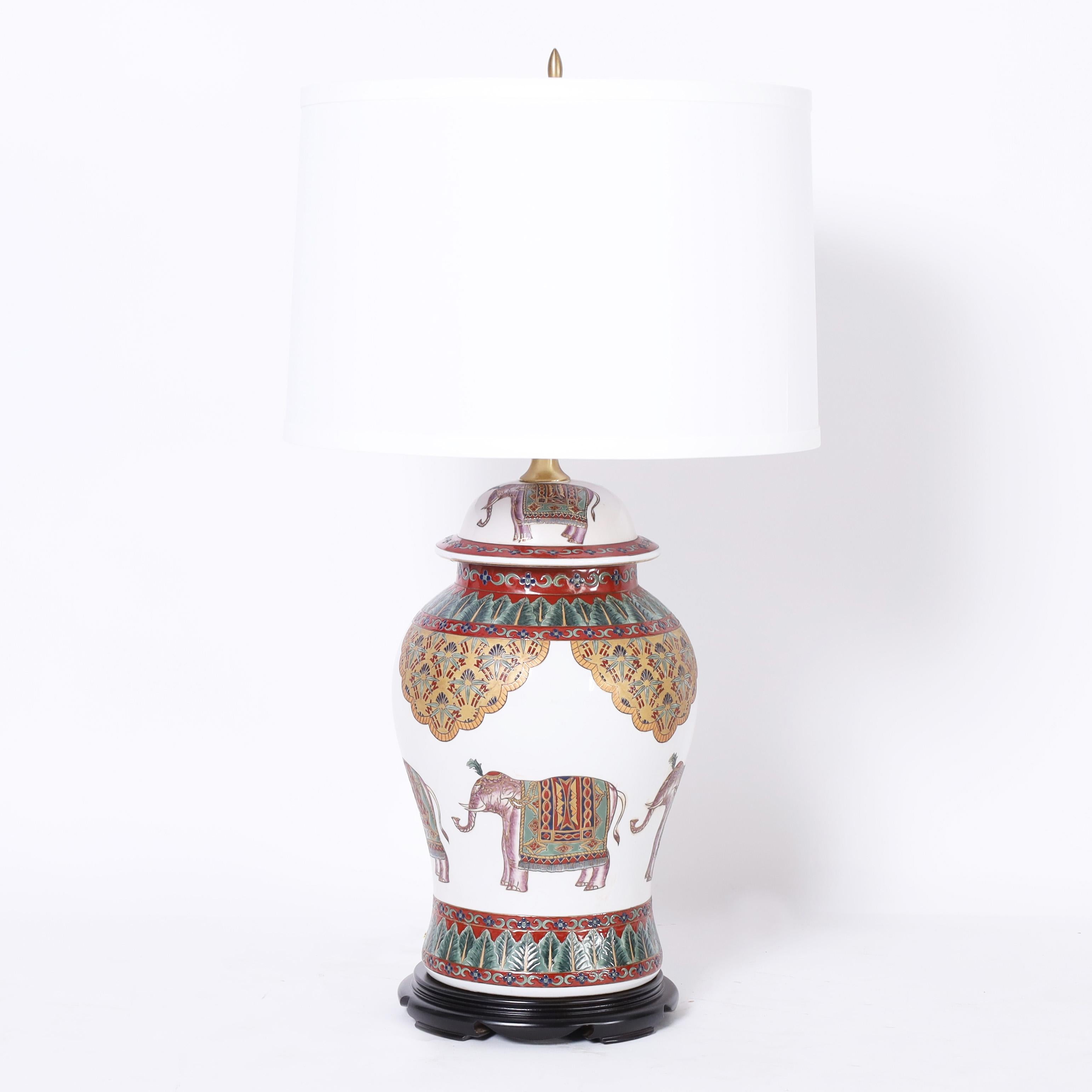 British colonial style pair of porcelain table lamps with classic ginger jar form hand decorated with elephants and floral motifs. Signed Oriental Accent on the bottoms.