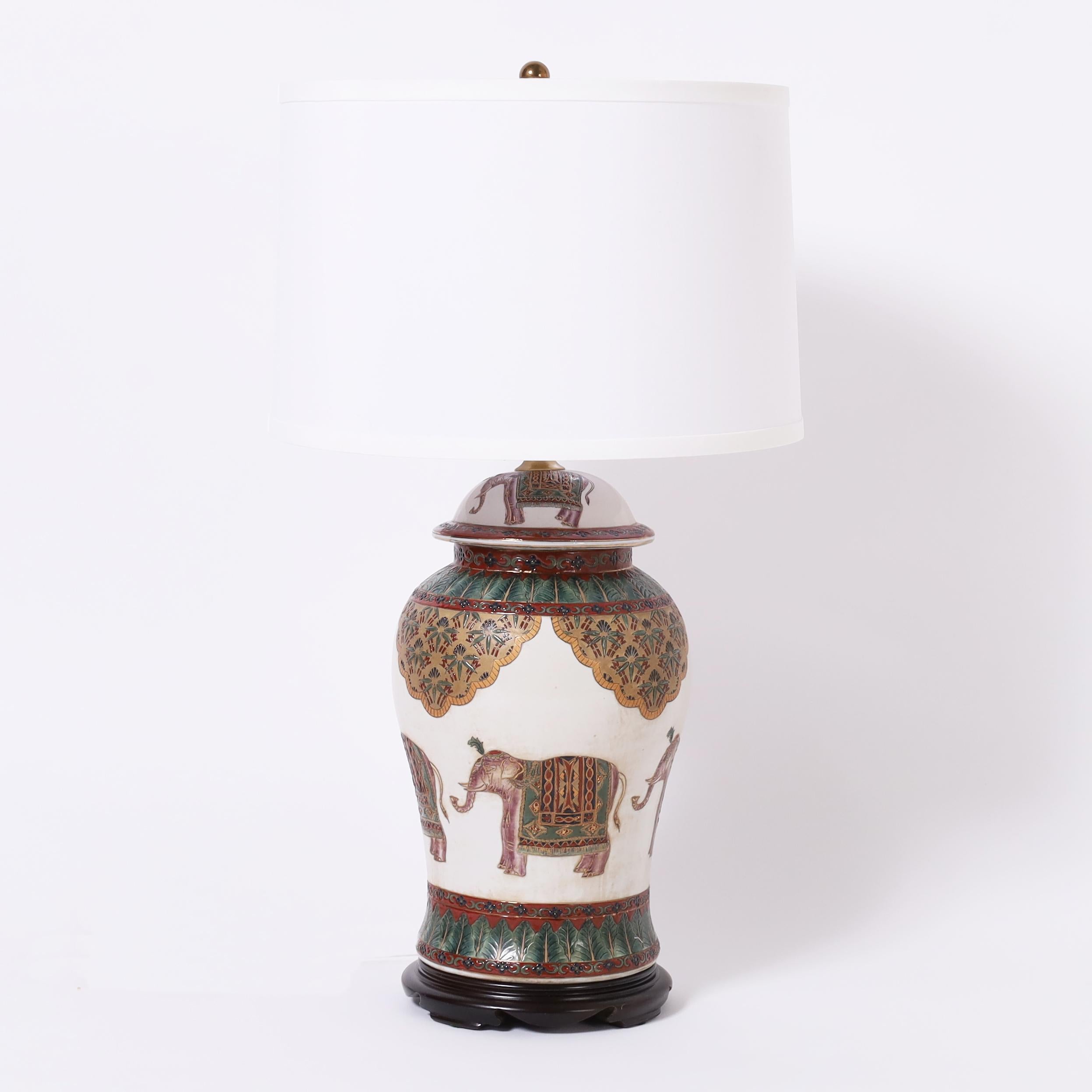 British Colonial style pair of porcelain table lamps with classic ginger jar form hand decorated with elephants and floral motifs. 