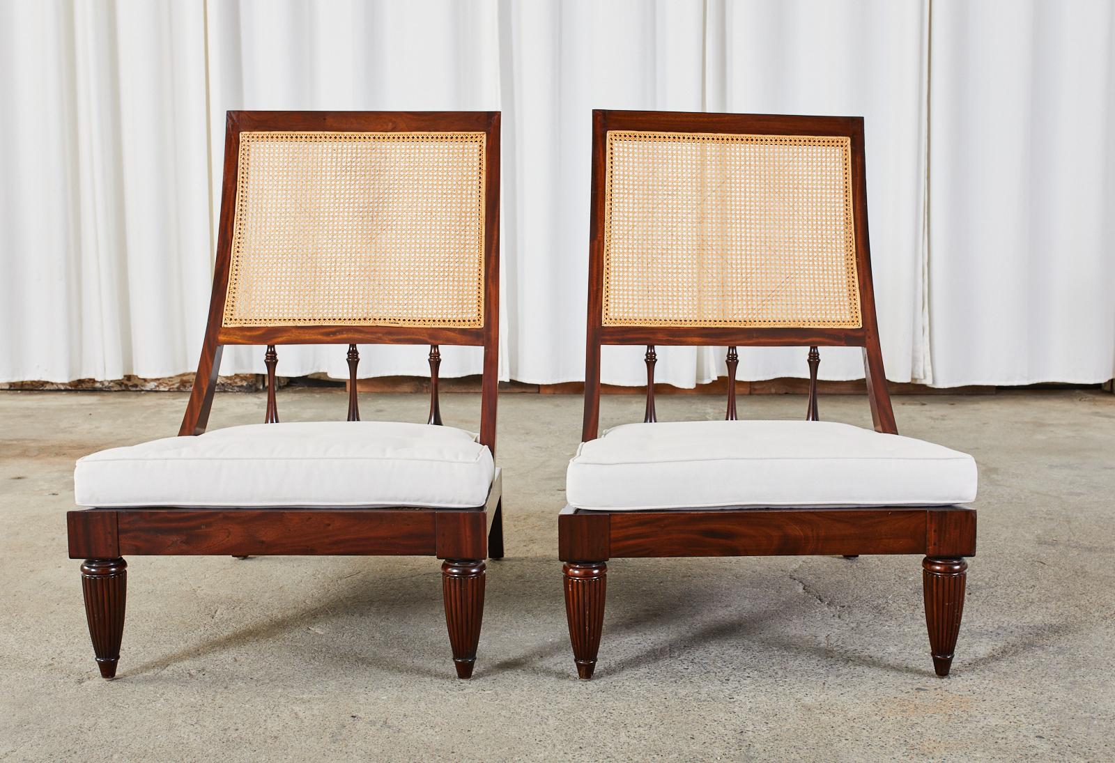 Handsome pair of Anglo-Indian plantation lounge chairs or campeche chairs hand-crafted from teak. The chairs feature a hand-caned seat and back. The frames are constructed from radiant grained teak with a gracefully curved back supported by baluster