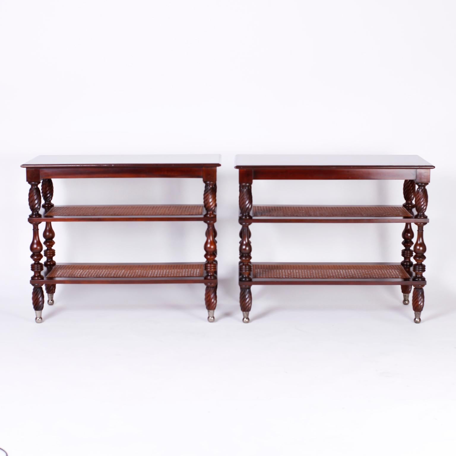 Pair of British colonial stands crafted in mahogany with three tiers, the middle and bottom being caned, with turned supports on nickel feet. Signed Baker Milling Road on the bottom.