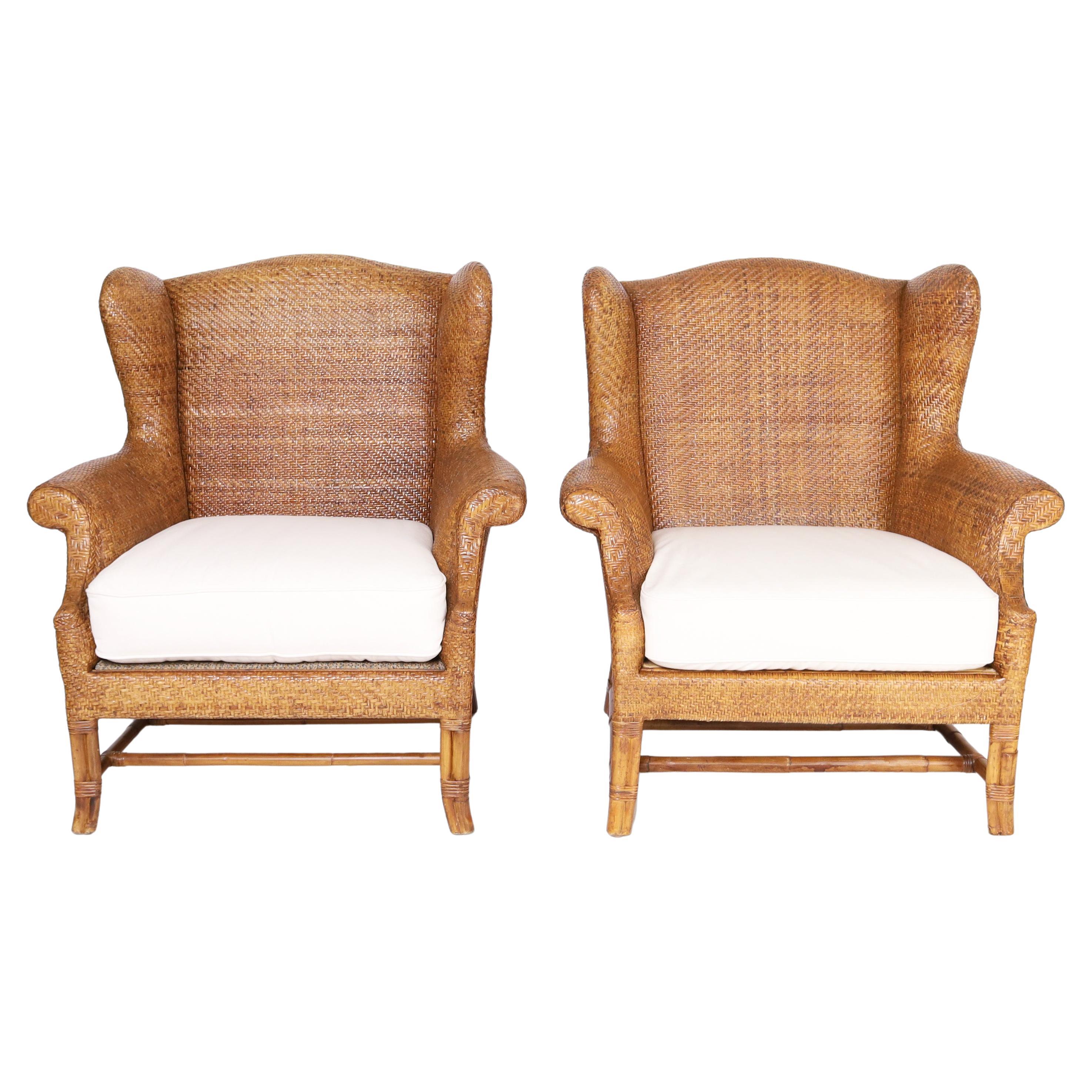 Handsome pair of British Colonial style wingback armchairs crafted with woven reed, in a herringbone pattern over classic form with bamboo legs and stretchers. Signed Milling Road for Baker.

