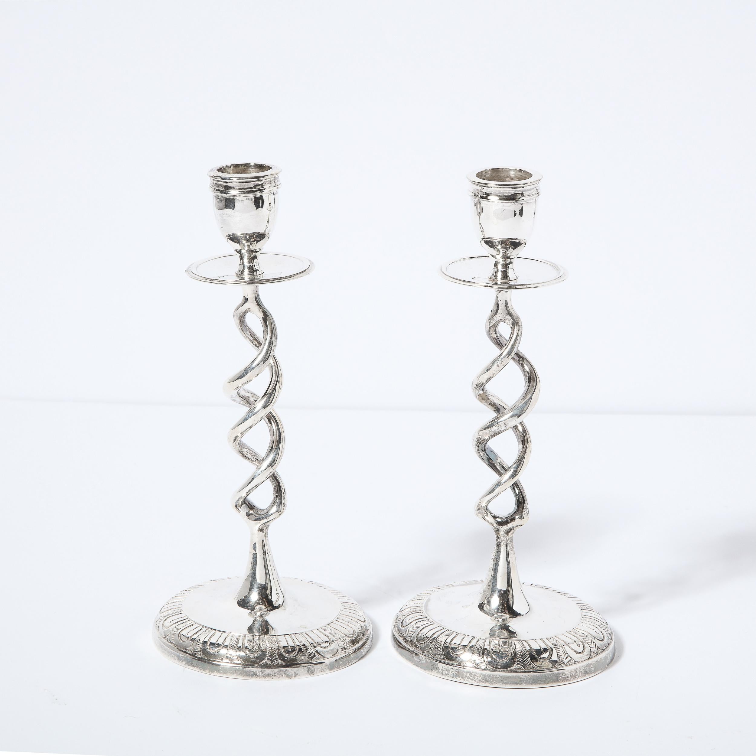 This elegant pair of Mid-Century Modern candle holders were realized in England circa 1960. They offer circular bases with hand etched geometric designs that ascend into a sculptural helix form body. The top features circular beveled bobeches and a