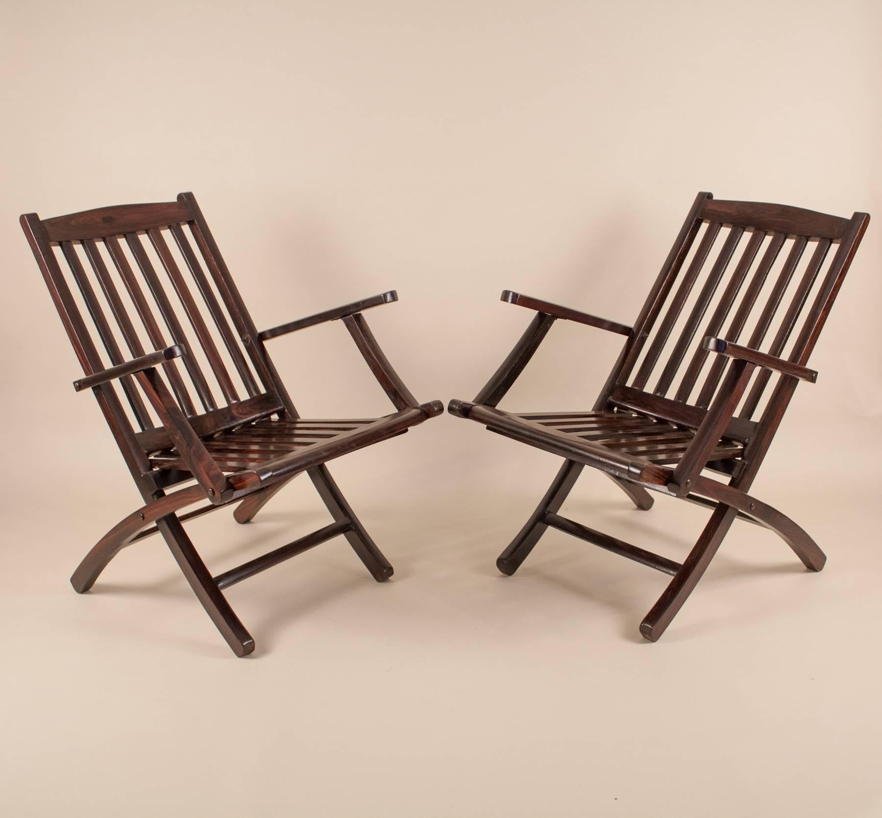 This pair of British folding steamer chairs evokes the romance of a mid-century voyage across the Indian ocean. As stylish as they are practical, these portable deck chairs have beautiful lines and are crafted from richly refinished rosewood. The