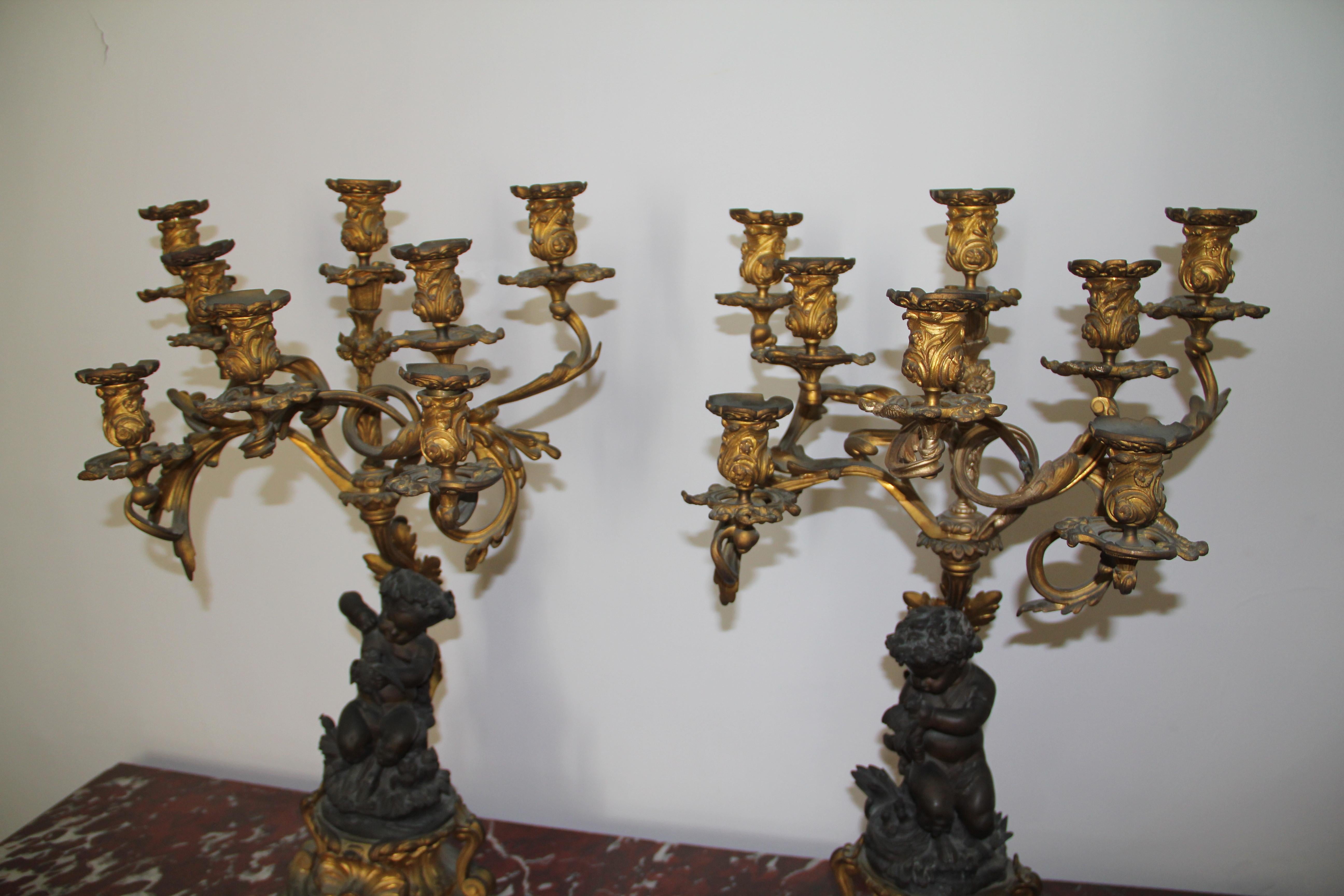 A pair of elegant eight scrolling candle-branches above seated figures of bacchanalian Satyrs holding birds on scrolling plinths cast with shells, 
The modelling of the satyrs, one with a dove and chicks in nest, the other with owls, is