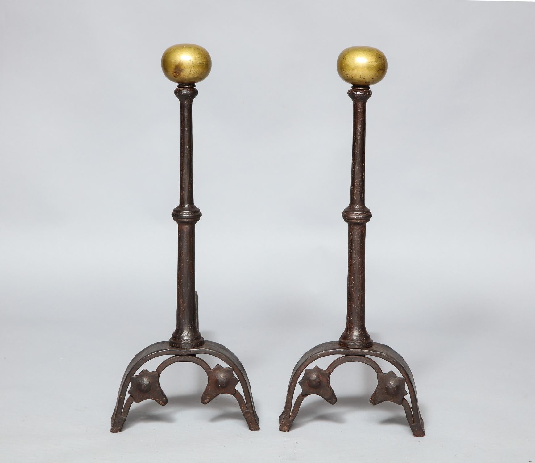 Fine pair of Arts & Crafts bronze and wrought iron andirons having suppressed ball finial over hand forged shafts with central collar, over arched base with trefoil arches, all with nicely patinated surface.