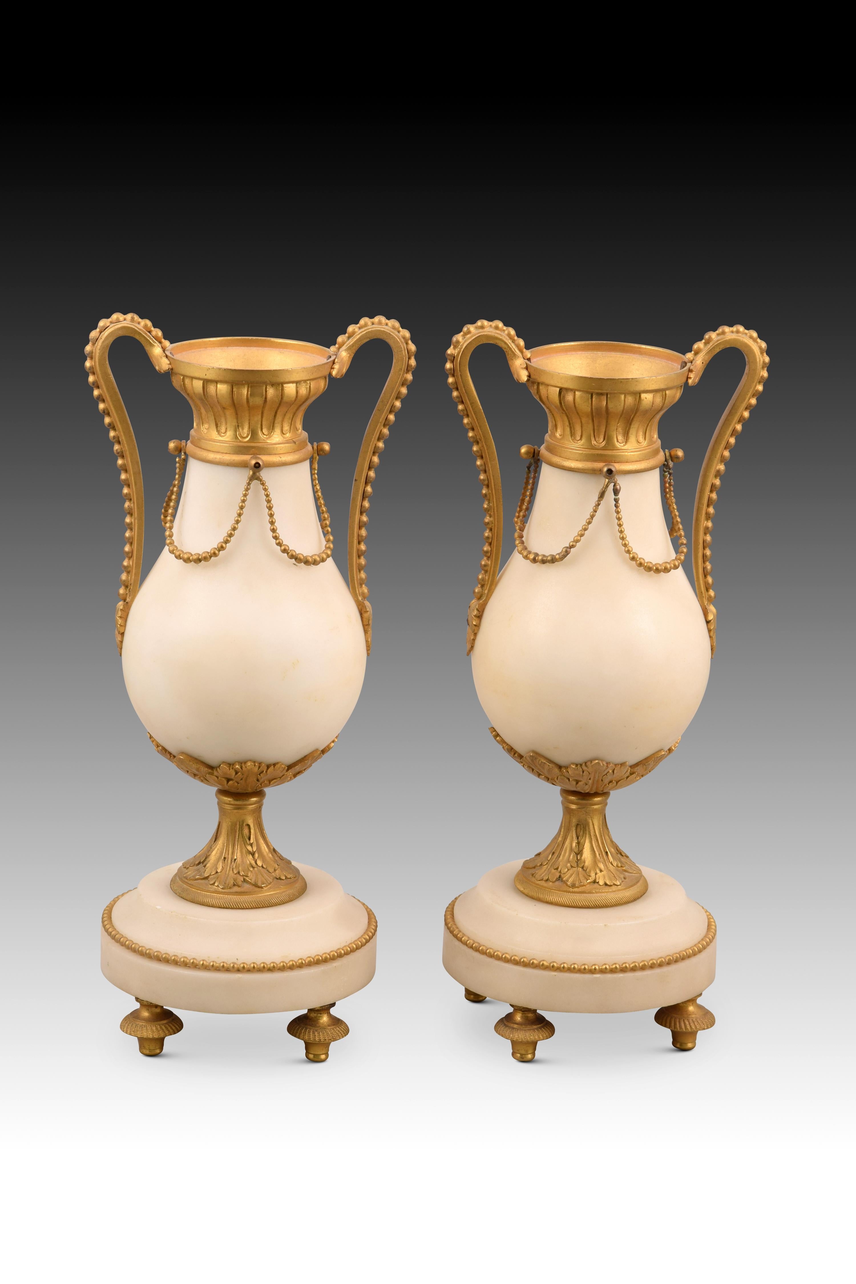 Pair of vases. Bronze, marble. XIX century.
 Pair of vases made of carved light marble with a stepped and circular base of the same material that also have decorative details in gilded bronze (strings of pearls, necks with architectural elements,