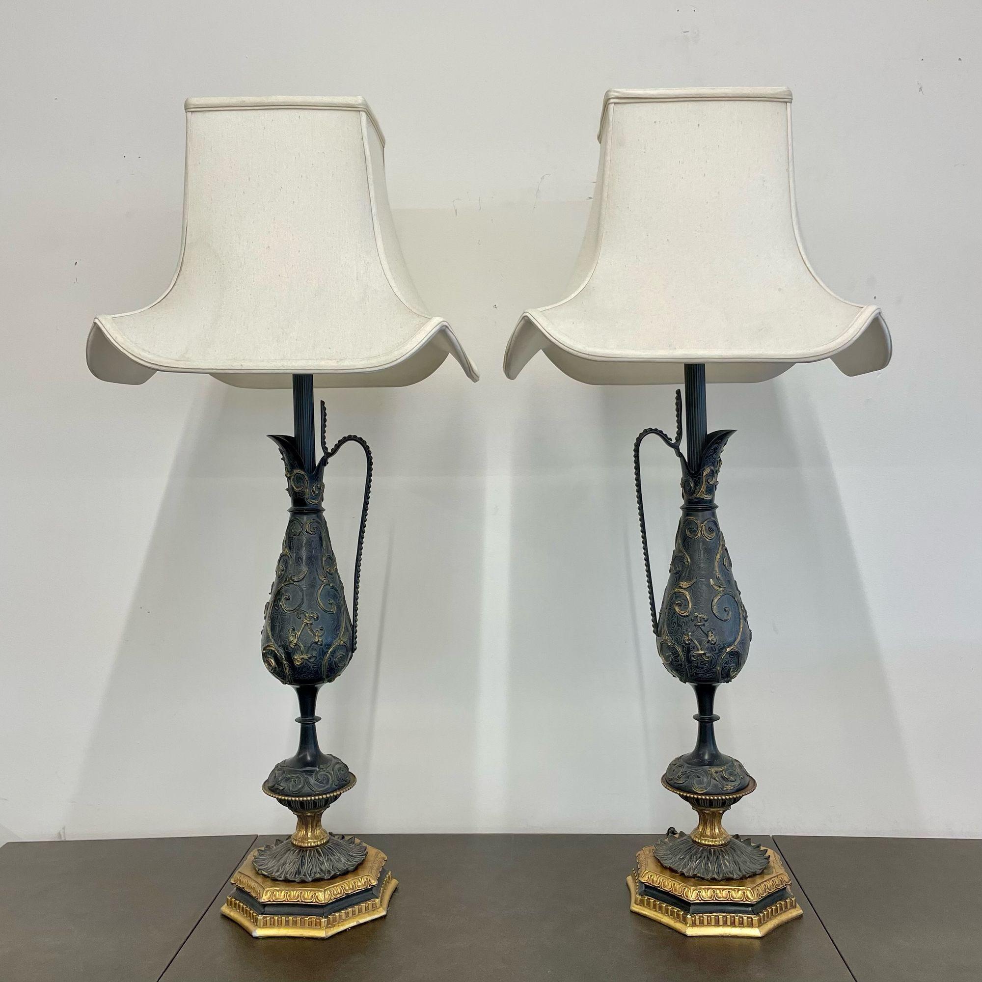 A Pair of Neoclassical Bronze and Metal Urn Form Table Lamps
 
A finely cast pair of water urns each having a large handle. The pair sitting on bases having a scroll and floral design with a mixed metal depicting gold overtones. Lamps are in need of