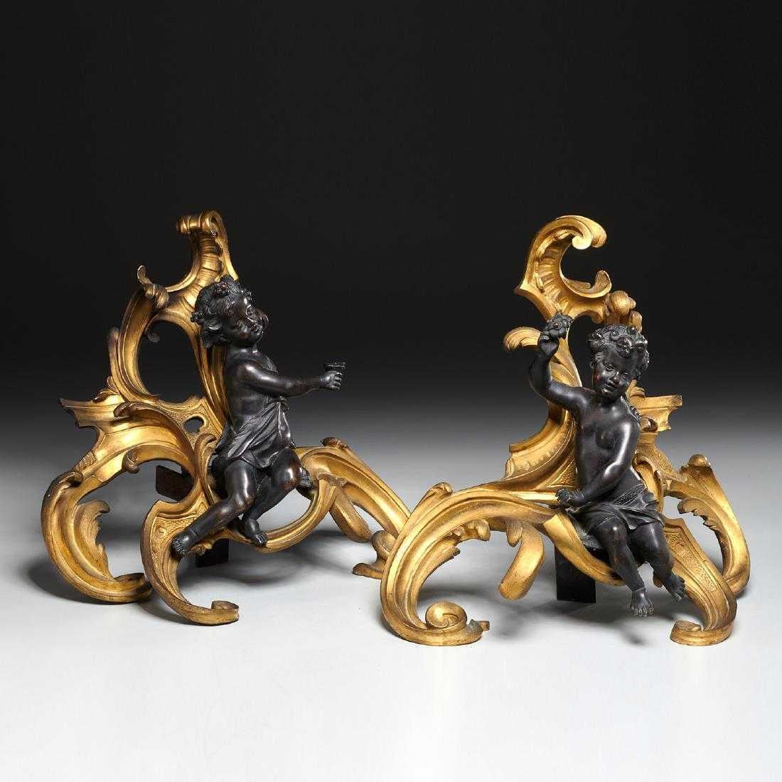 Fine pair of Baroque Bronze and ormolu Louis XV style French Chenêts depicting two putti in dark bronze patina sitting amidst a flamboyant décor of gilt ormolu rocaille. modeled after Clodion.