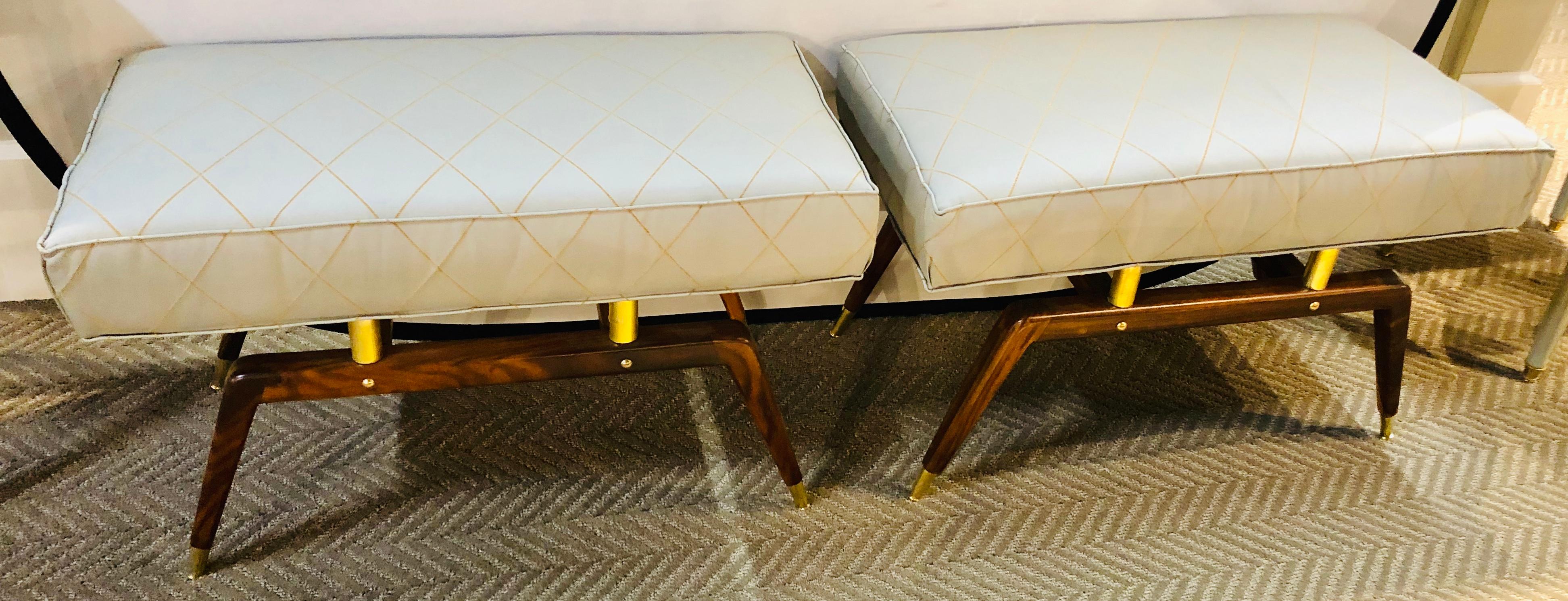 Pair of bronze and walnut Mid-Century Modern footstools or window bench each having brass capped feet and brass column-form supports from U-shaped base. Each having new upholstery.