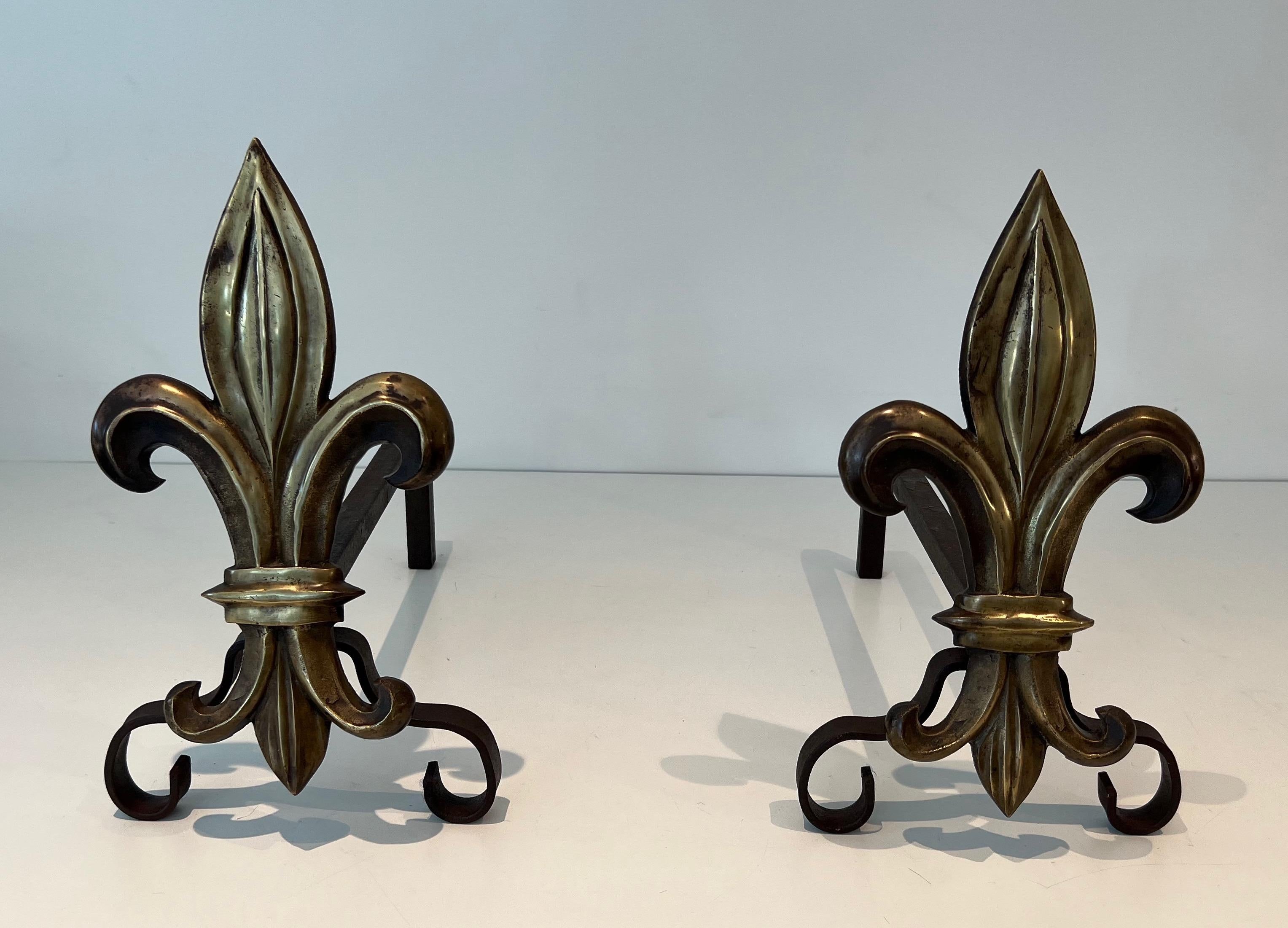 Cette paire de chenets est composée d'une fleur de lys en bronze et de fer forgé. Yjis est une œuvre française. Circa 1940