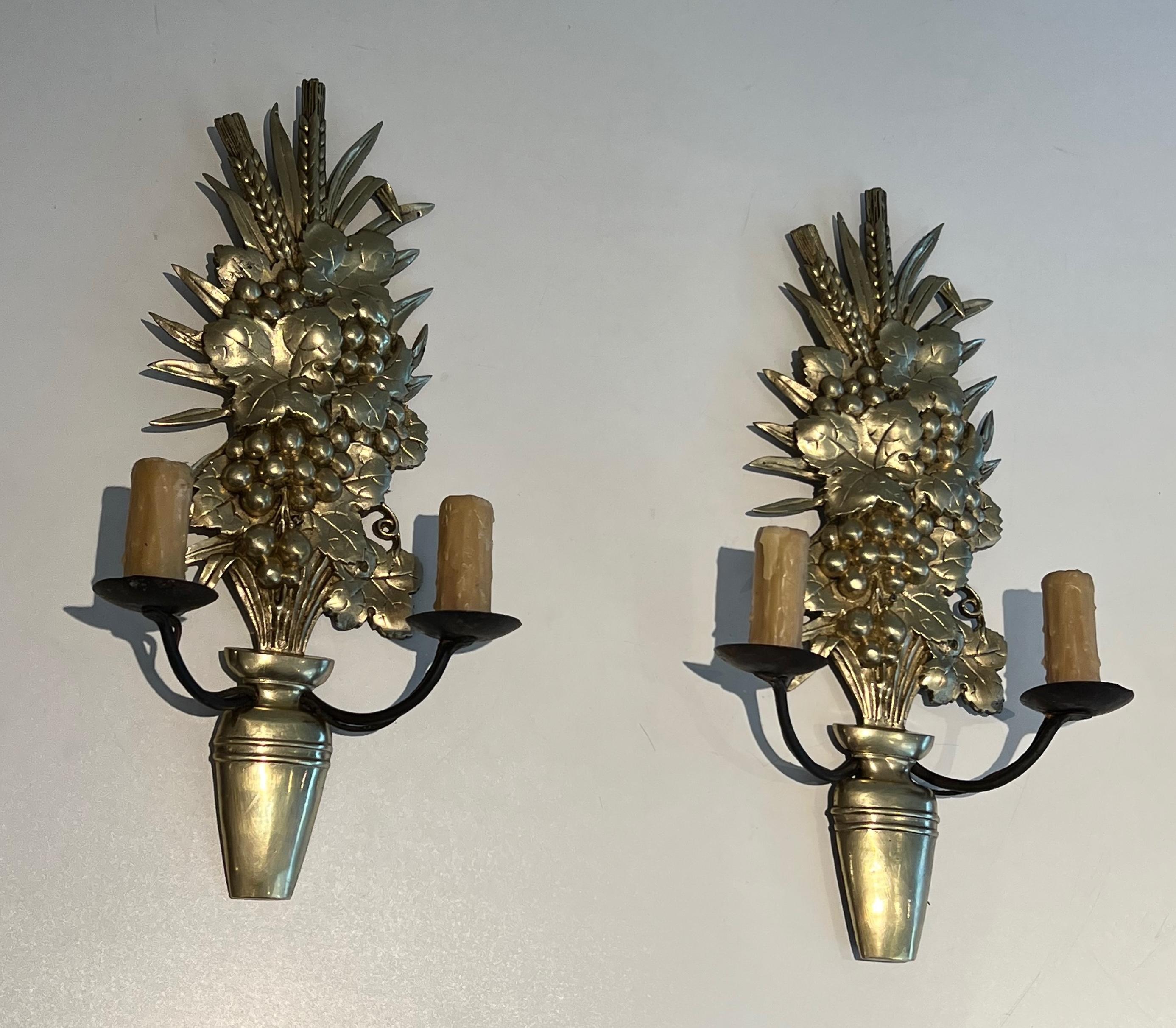 Este bonito par de apliques de pared está formado por una pieza decorativa de bronce que representa un frutero con brazos de hierro forjado. Se trata de una obra francesa. Alrededor de 1970