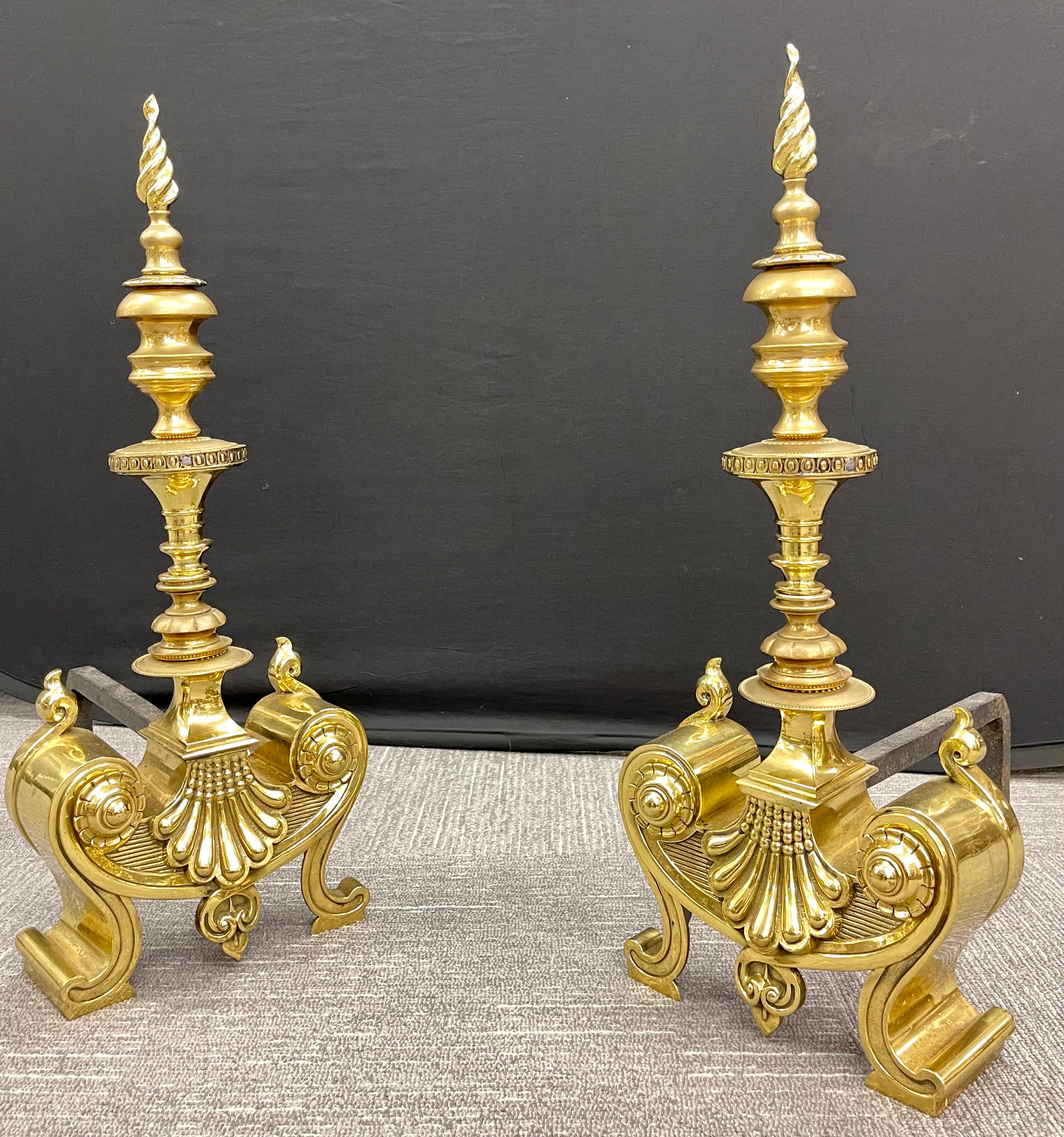 Pair of bronze andirons. Large and impressive andirons having been polished. Louis XVI in style having a flame top supported by a column center stem leading to a very decorative base of shell design.