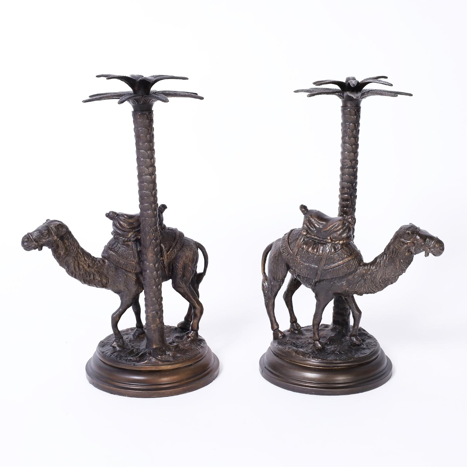 
Pair of British colonial style cast bronze candlesticks with palm tree candle holders over saddled camels on faux terra firma bases.
     