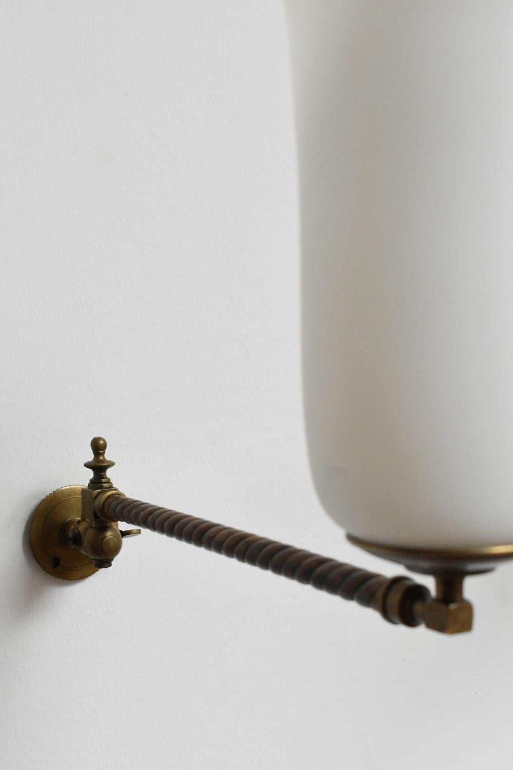 Pair of bronze articulated wall sconces holding a white opaline glass. England, XIXth c.