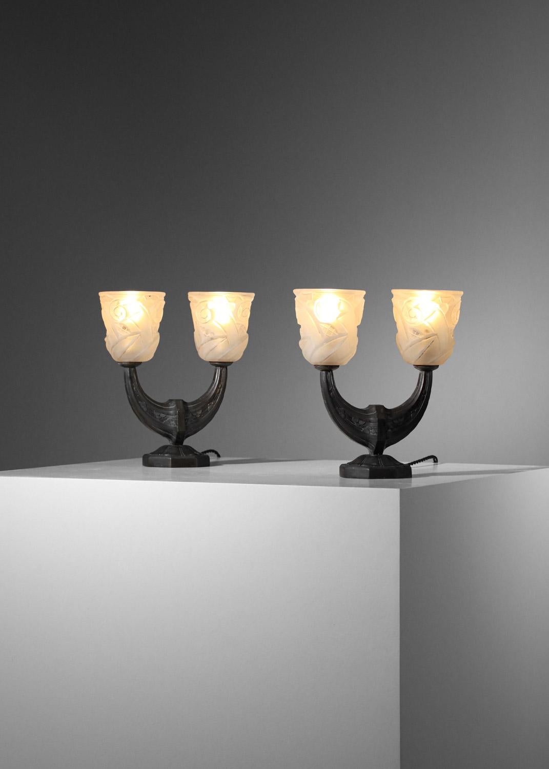 Sehr schönes Paar französischer Art-déco-Nachttischlampen aus den 1930er Jahren. Sockel der Lampen aus massiver Bronze, patiniert und mit typischen Art-Déco-Motiven verziert. Lampenschirm aus weißem, opakem Glas, geformt in Form einer Tulpe mit