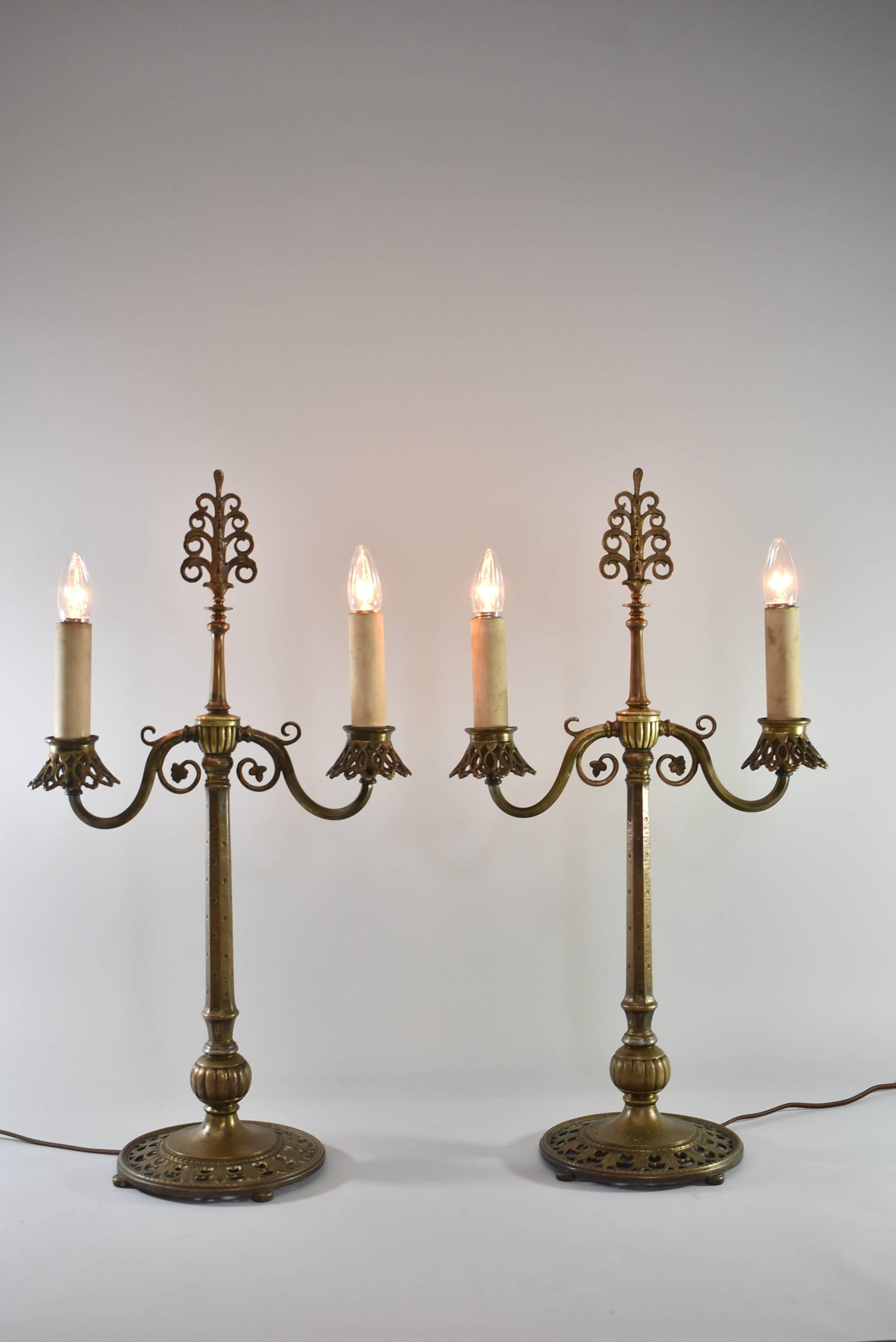 A fantastic pair of buffet lamps by Oscar Bach. Candelabra with two electrified candle sockets on each with mica shades that are included. They have the original bronze candle covers but can be changed out for newer covers. Signed on the base,