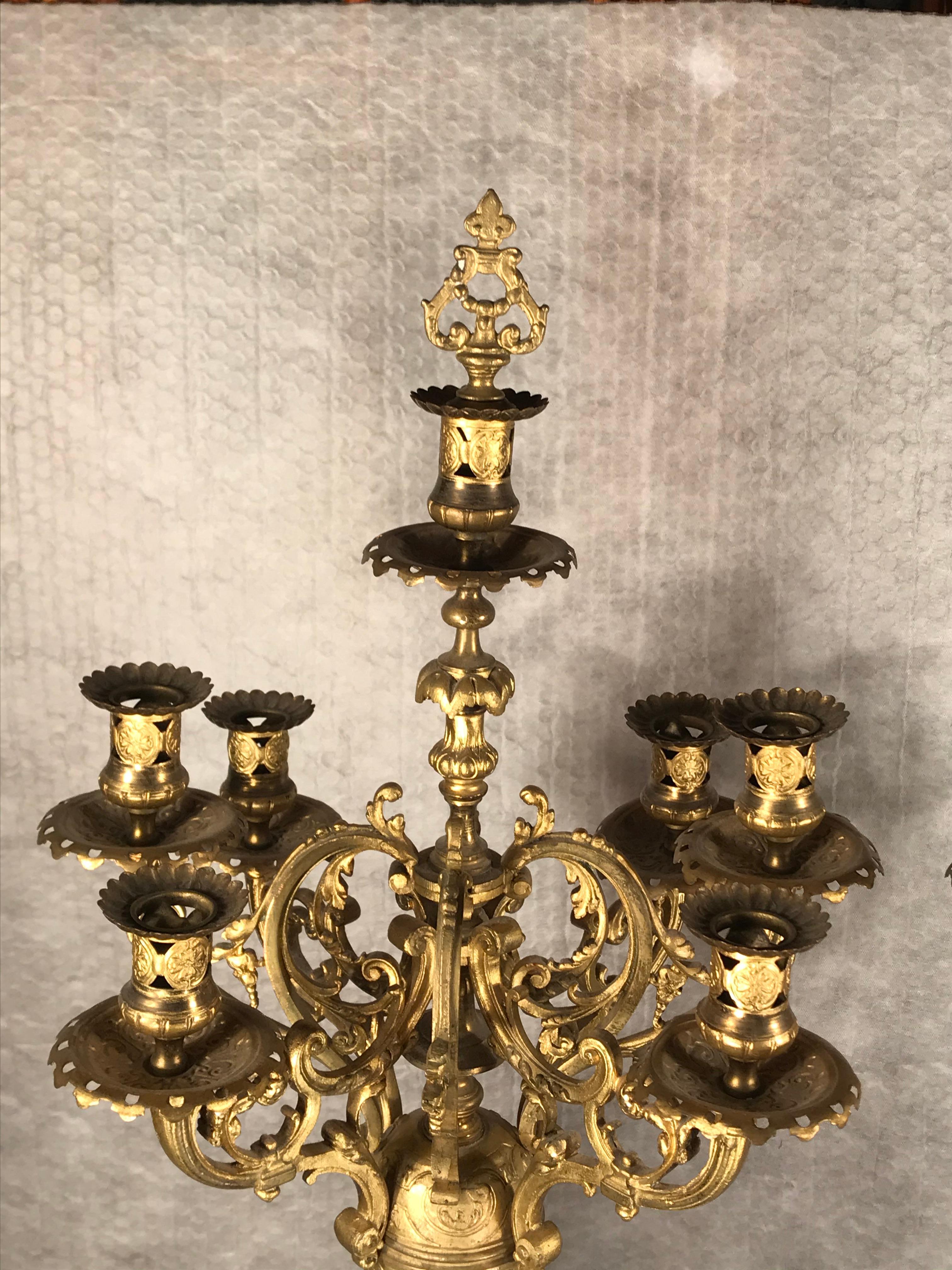 Pair of bronze candelabras, France 19th century. The Historicism candelabras have 7 candleholders. They are decorated with rocaille, latticework and mascaron decor.
They are in very good condition. 
The candelabras are part of a three piece set with