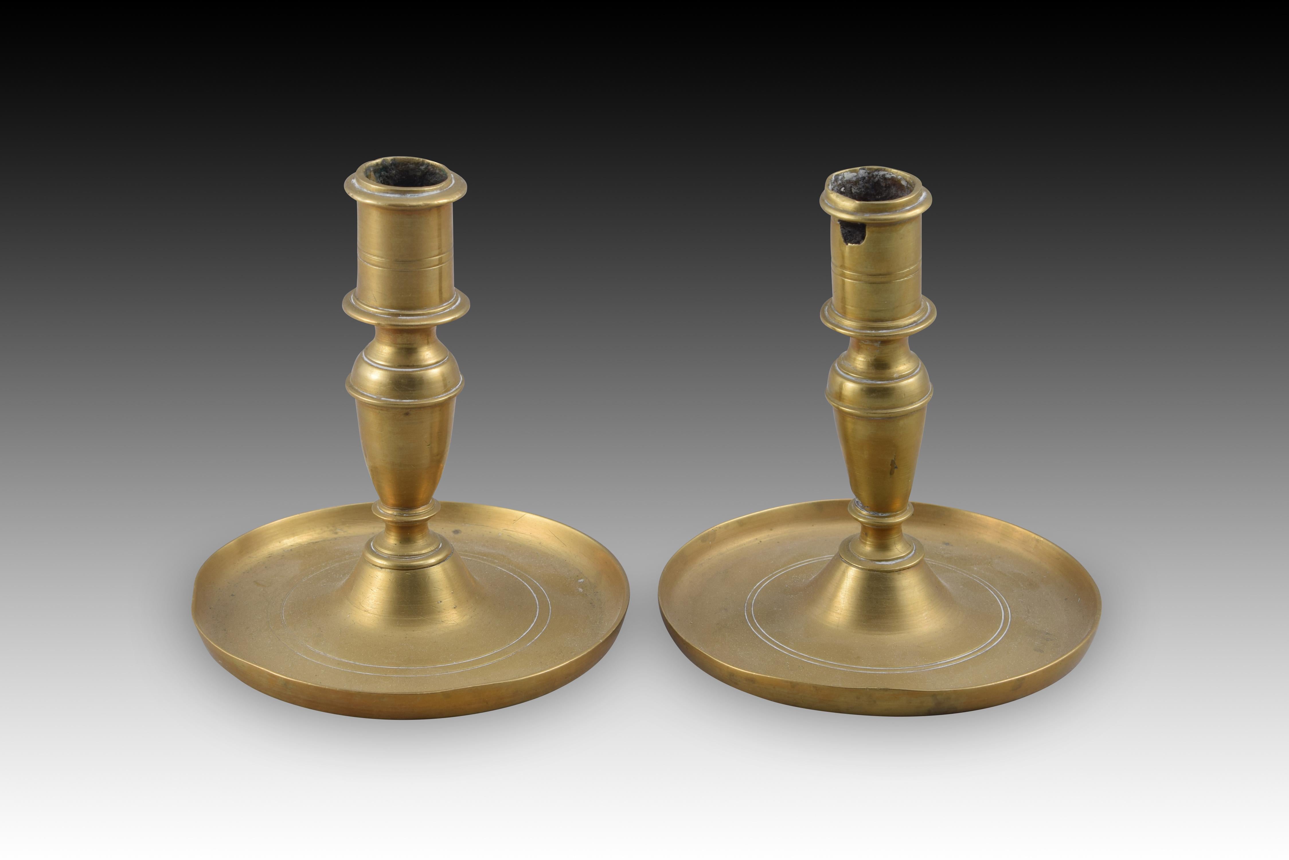 Pair of candlesticks. Bronze. XIX century. 
Pair of candlesticks with a circular base with a raised edge and decorated with two engraved lines, a vase-shaped
axis with fine smooth moldings and tubular lighters, decorated in a similar way to the
