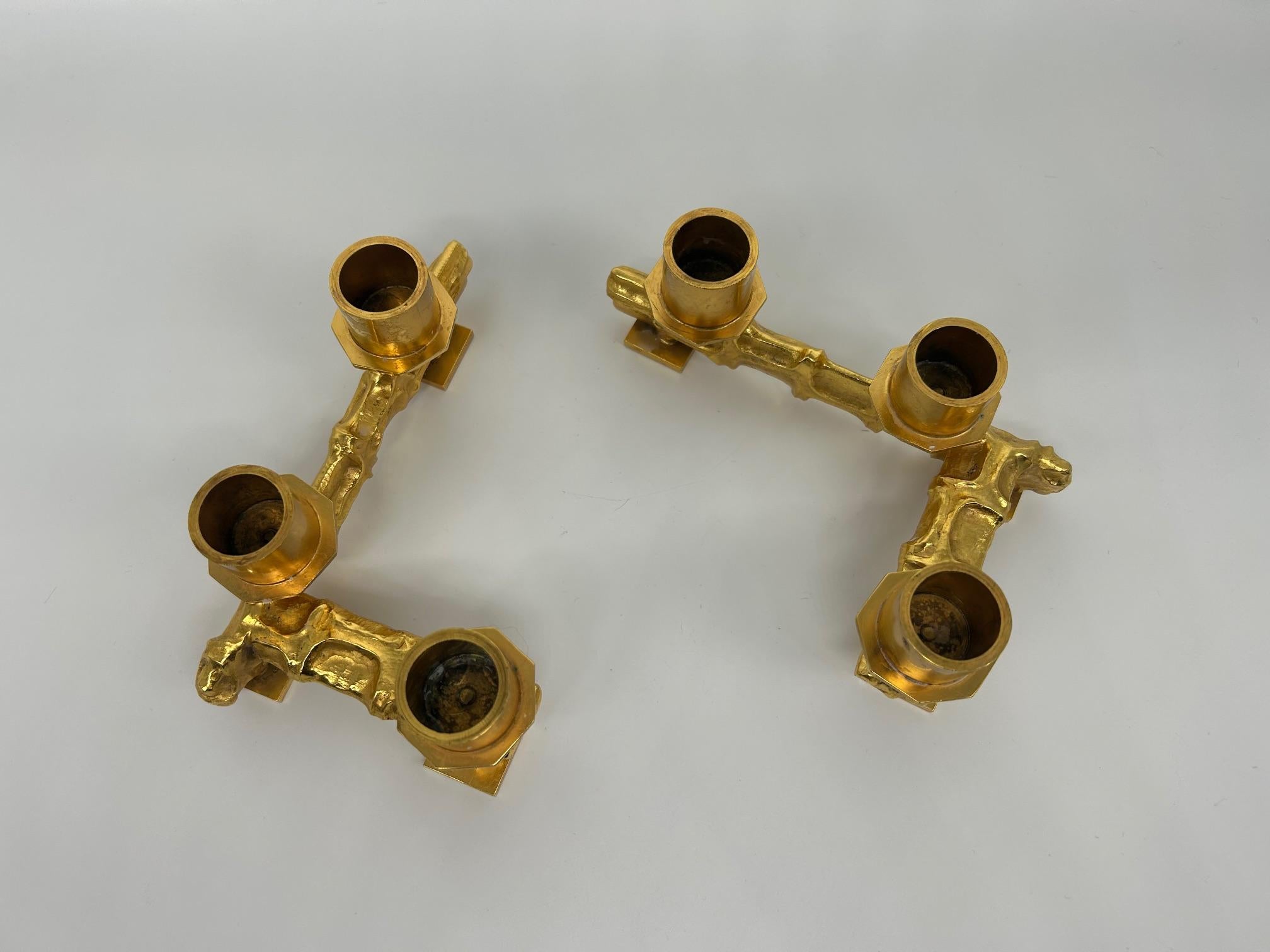 Eleganza e senza tempo, questa coppia di candelieri in bronzo martellato incarna perfettamente l'estetica raffinata degli anni Settanta. La lavorazione del metallo, martellata a mano, crea sottili giochi di texture che catturano magnificamente la