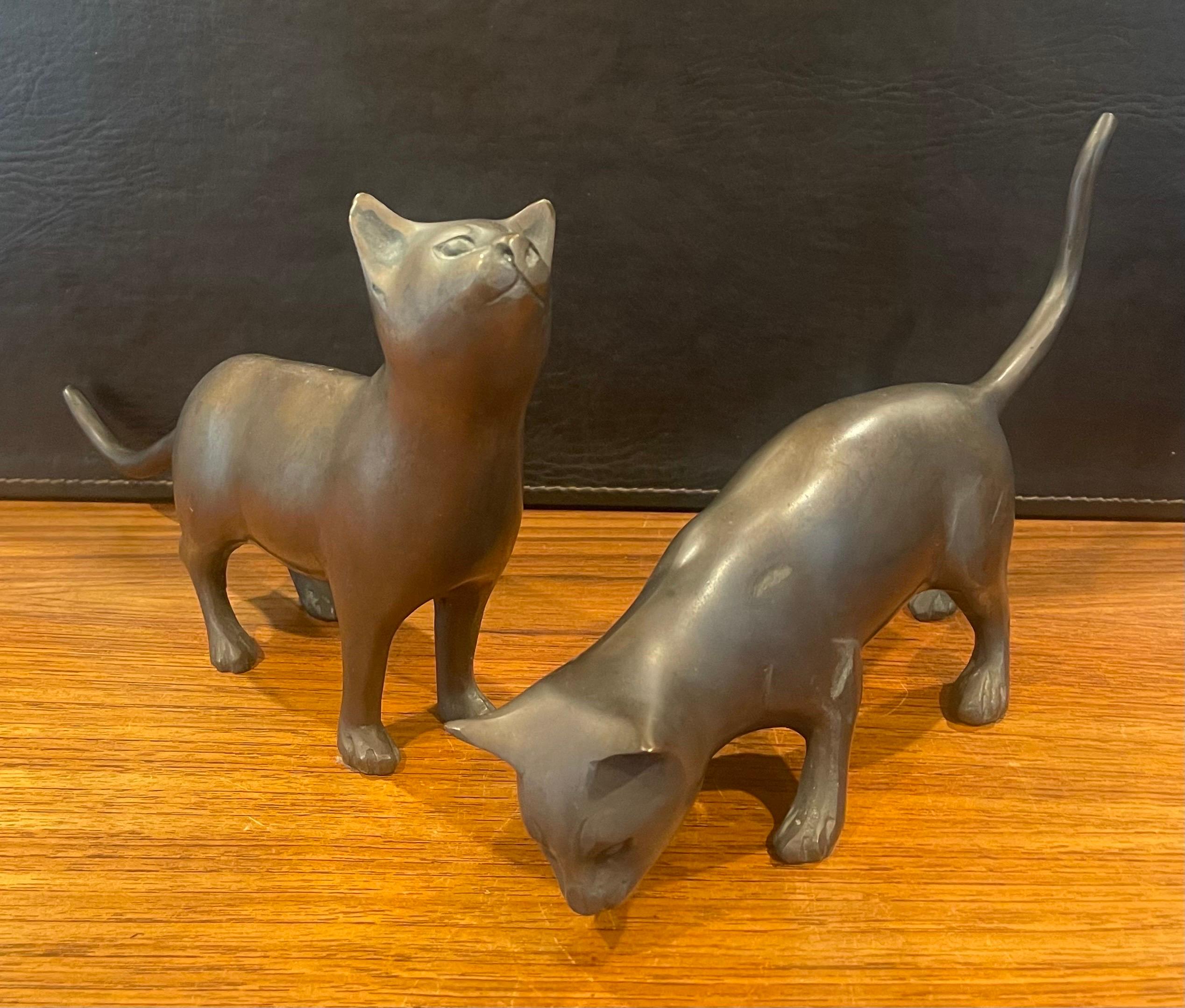 Superbe paire de sculptures de chat en bronze, datant des années 1970. Elles sont en état d'origine avec une belle patine, quelques petites bosses et quelques rayures de surface. La paire mesure 12 