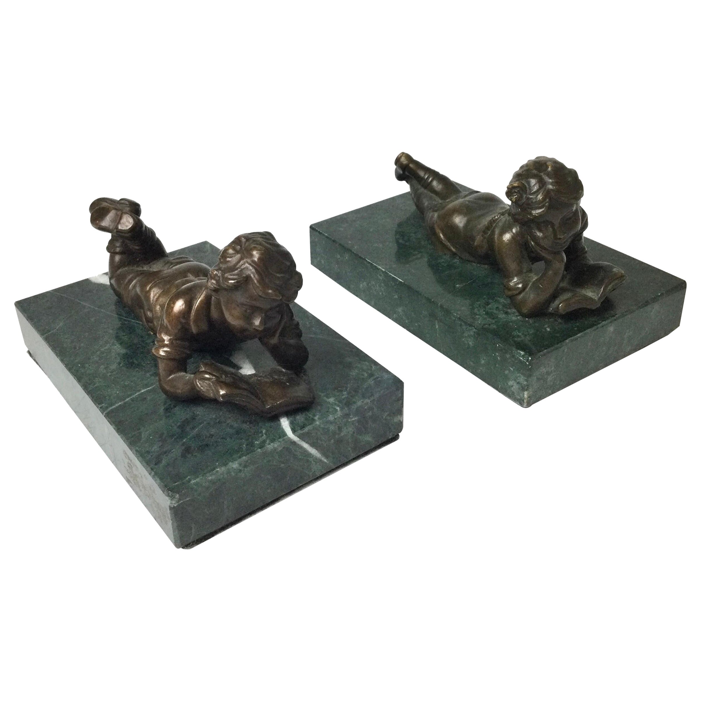 Pareja de niños de bronce leyendo sobre bases de mármol verde