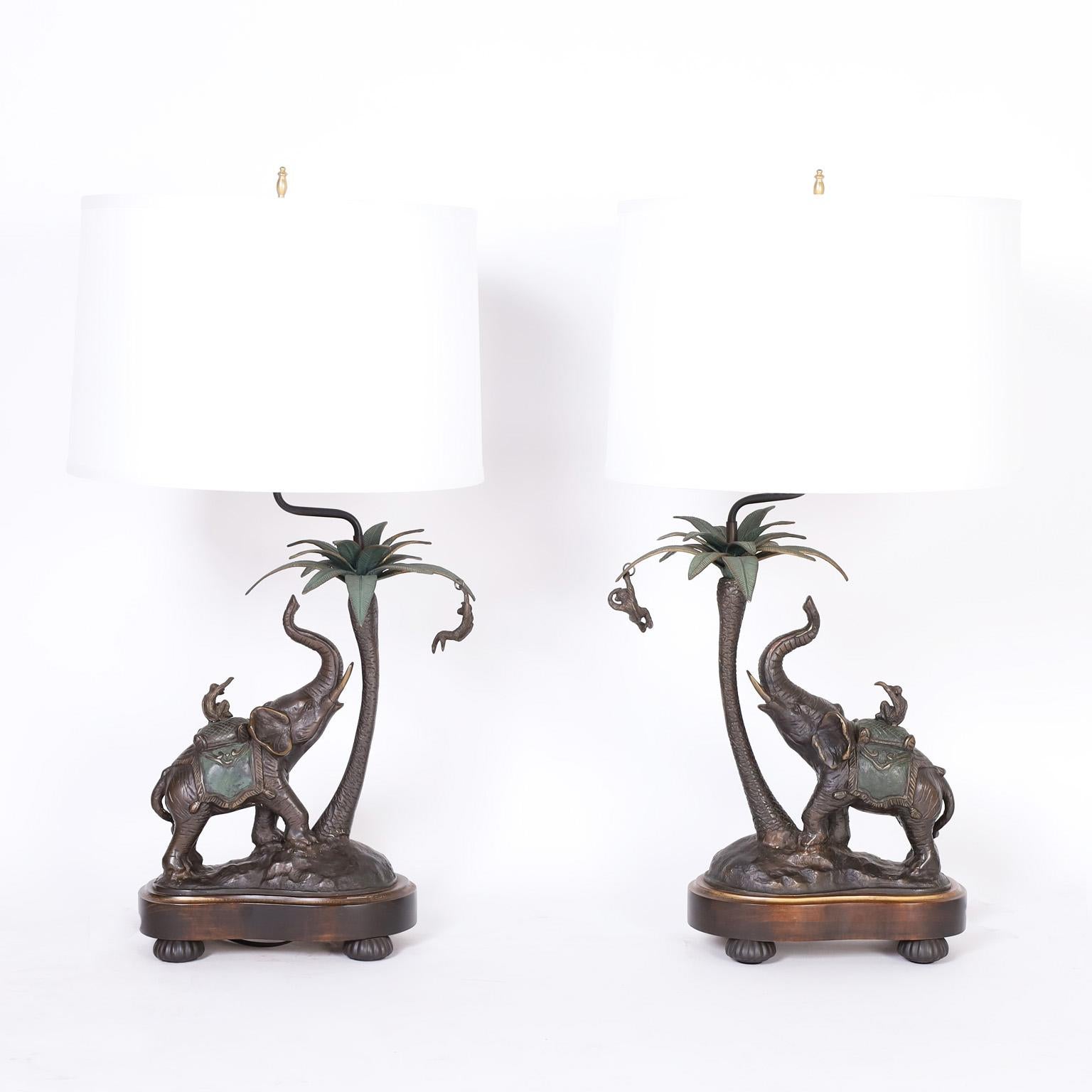 Pair of table lamps by Frederick Cooper with a bit of whimsy, crafted in bronze depicting a monkey riding an elephant under a palm tree with another monkey in it. Presented on an organic form wood base on beaded bronze feet.