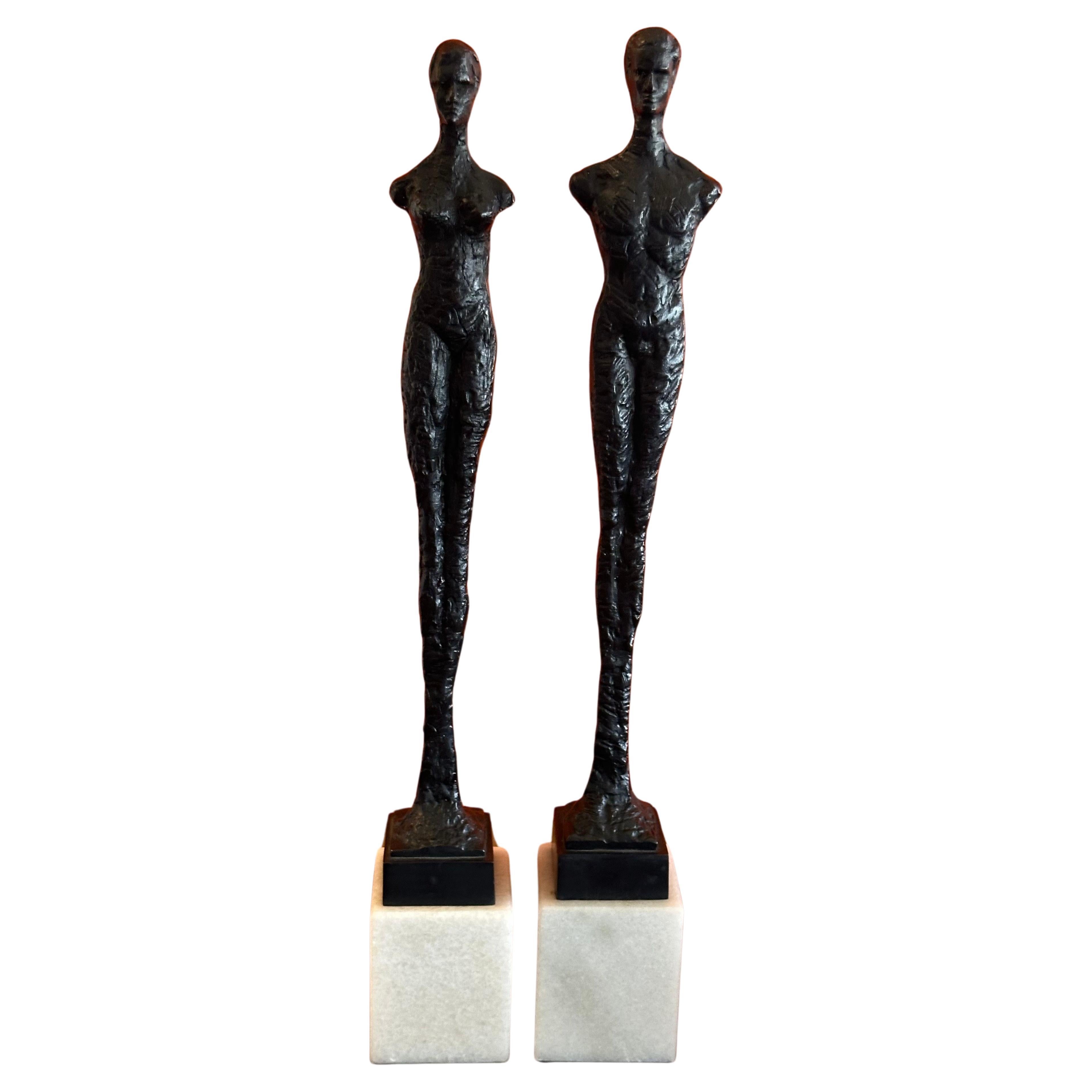 Pair of contemporary elongated bronze figurines on white marble bases in the style of Alberto Giacometti, circa 1980s. The male and female bronzes are in very good vintage condition and measure 3