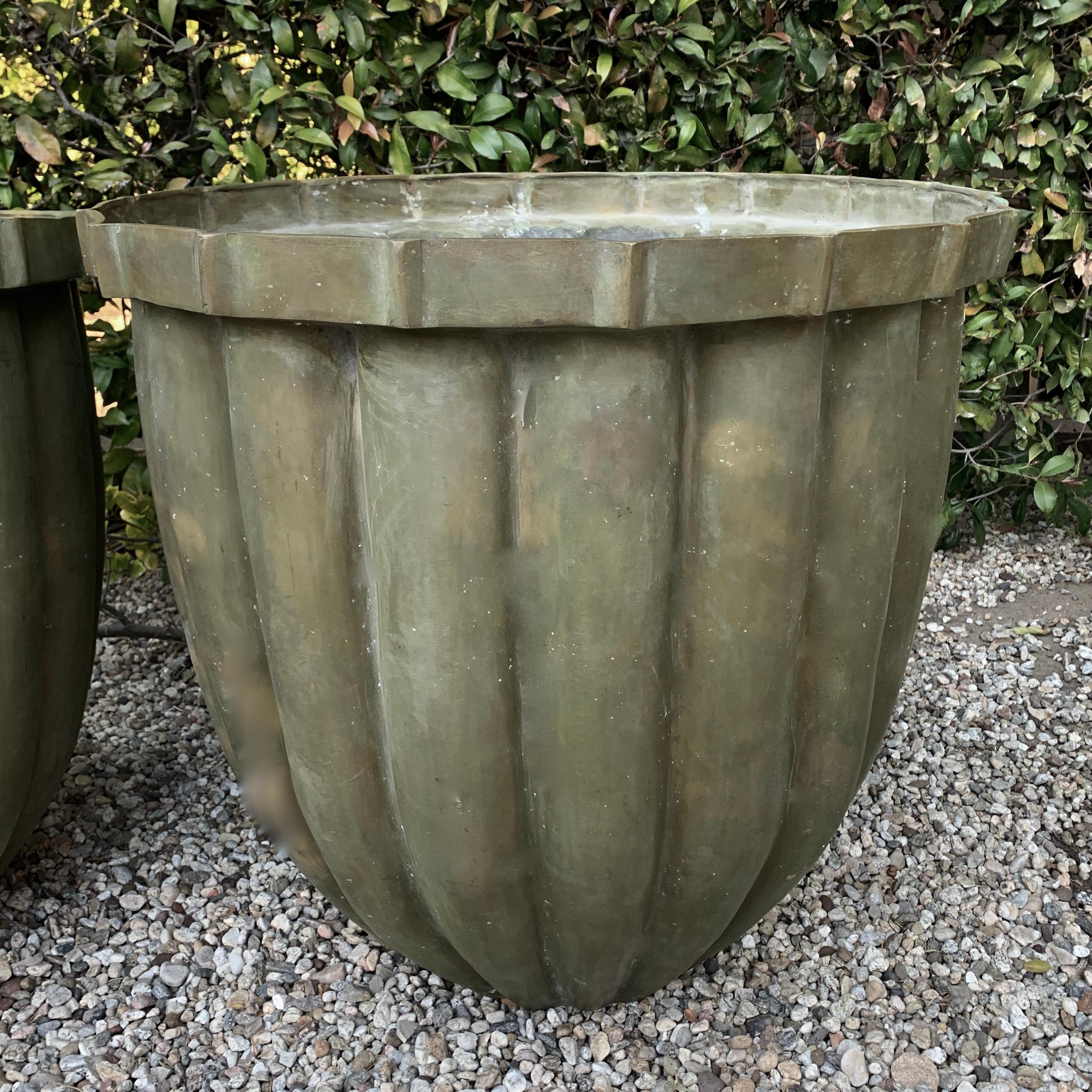 A monumental pair of solid bronze patinated fluted planters. The pair are a stunning pair and beautifully designed - a compliment to many spaces, from outdoor gardens to interiors. The planters are very large and heavy, they do not currently have