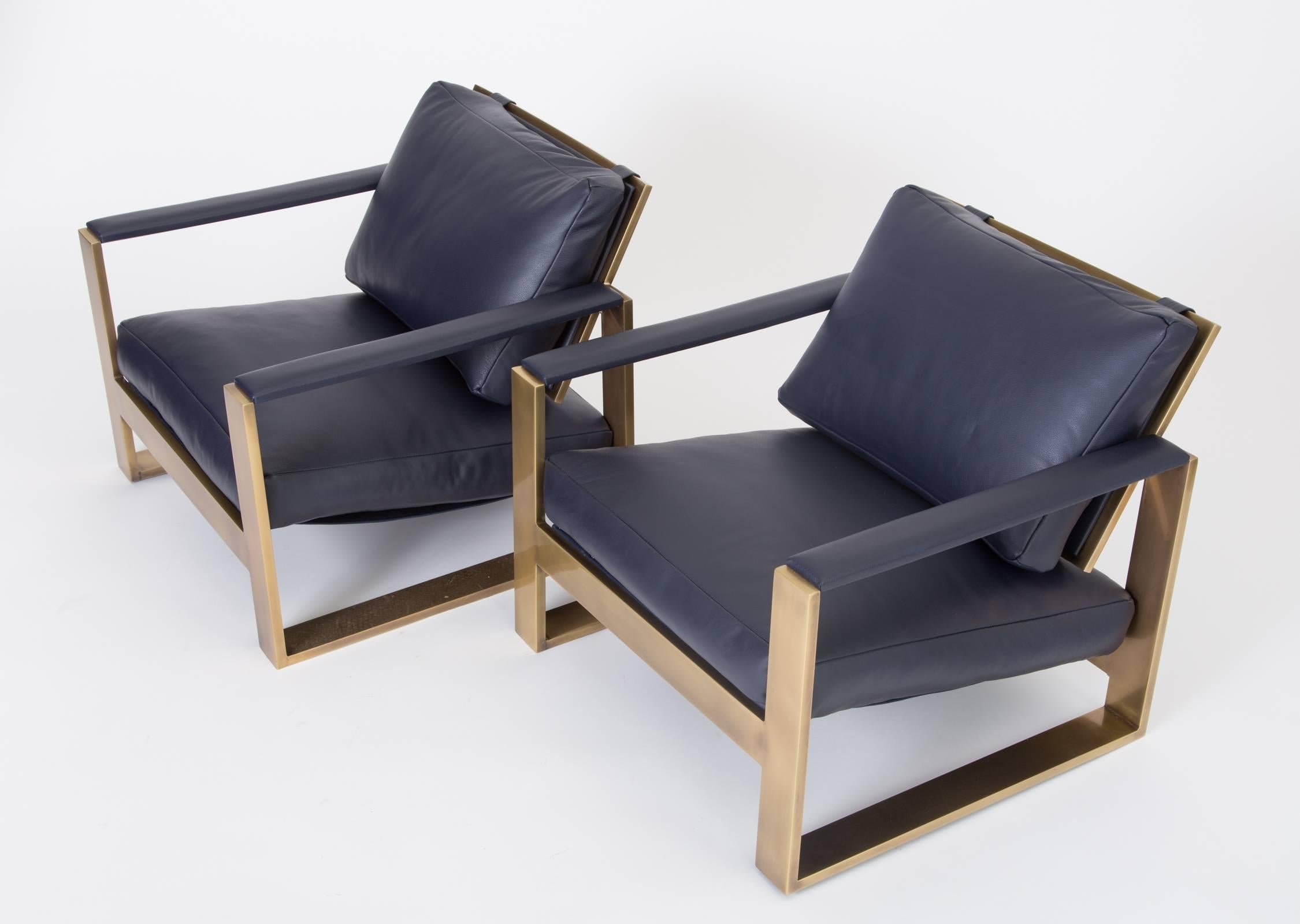 A fully restored pair of low lounge chairs by Milo Baughman for Thayer Coggin have a frame in flat bar bronze, with leather inlays and sumptuous down-filled cushions. Each chair is supported by a curved bar that acts as the legs and armrests, padded