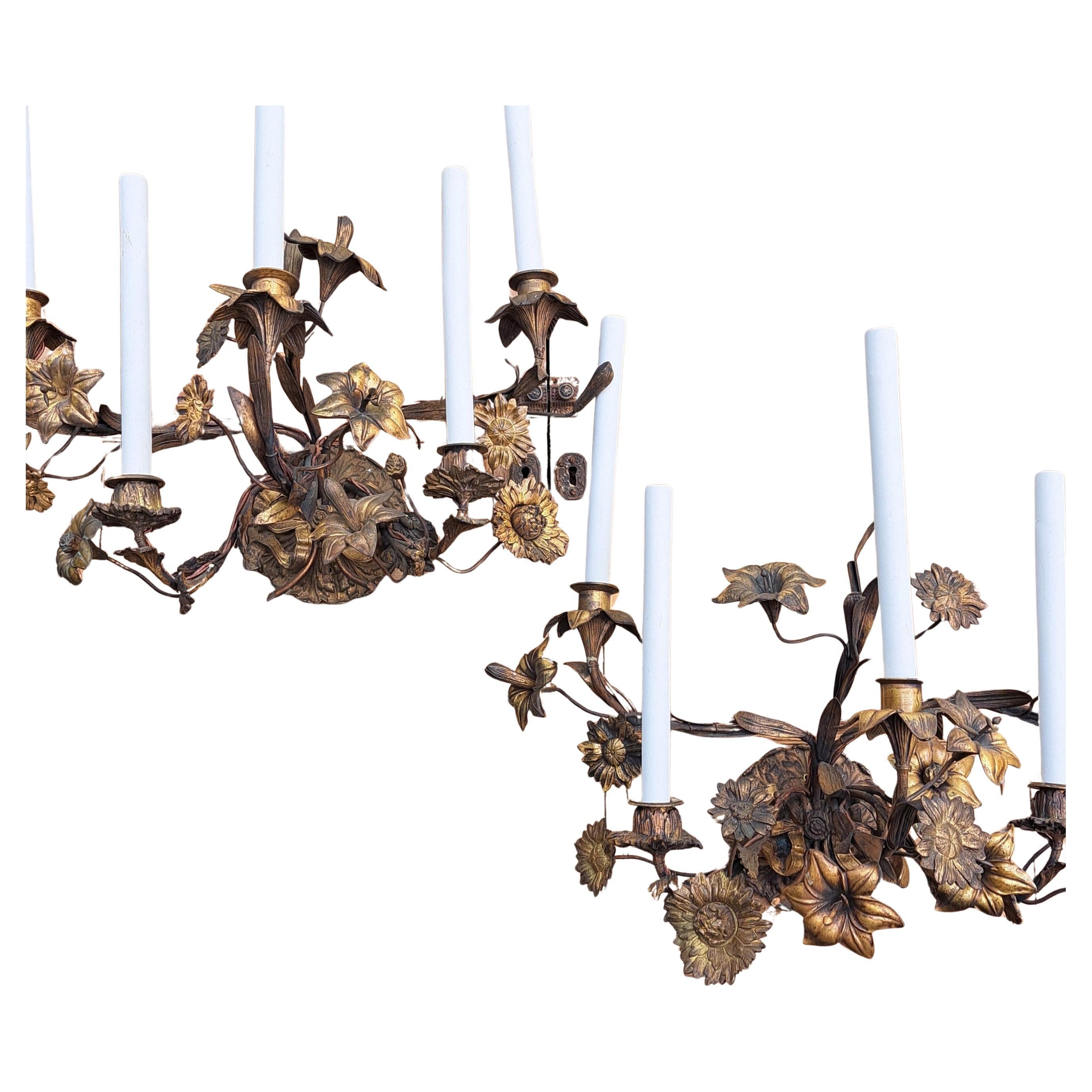 Grande coppia di appliques floreali francesi del 1900 circa. Ciascuna di esse è formata da un grande bouquet di gigli e margherite scabiose legate alla base con fiocchi di nastro. 5 luci ciascuna, bronzo patinato/ottone con riflessi dorati. Misura
