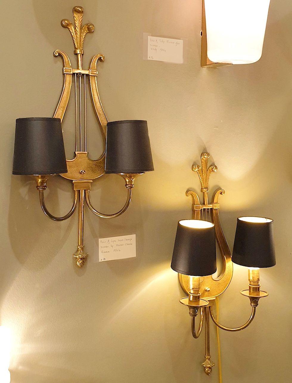 Pair of Lyre neoclassical style sconces, by Maison Charles, France 1950s.
The pair of sconces are made of bronze, and have 2 lights each.
Each light bulb is covered with a small black shade. The shades can be removed.
They are rewired for the