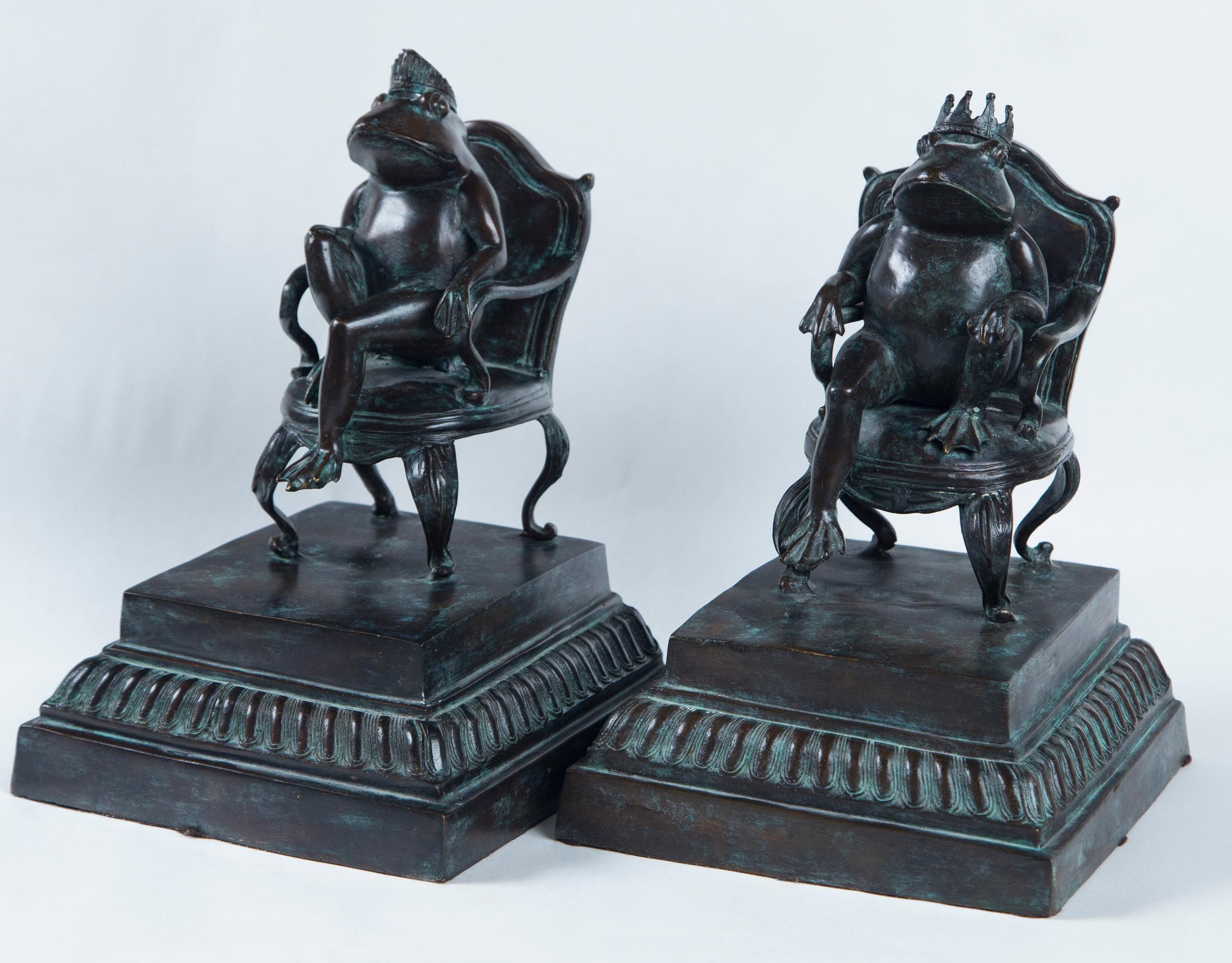 This whimsical pair of seated crowned frogs have a  vertigris  blue/green  patina
They sit in open arm chairs on top of integral stepped bases with gadrooned edging. The back are flat to go against the books. The 11.75 inches is the tallest.