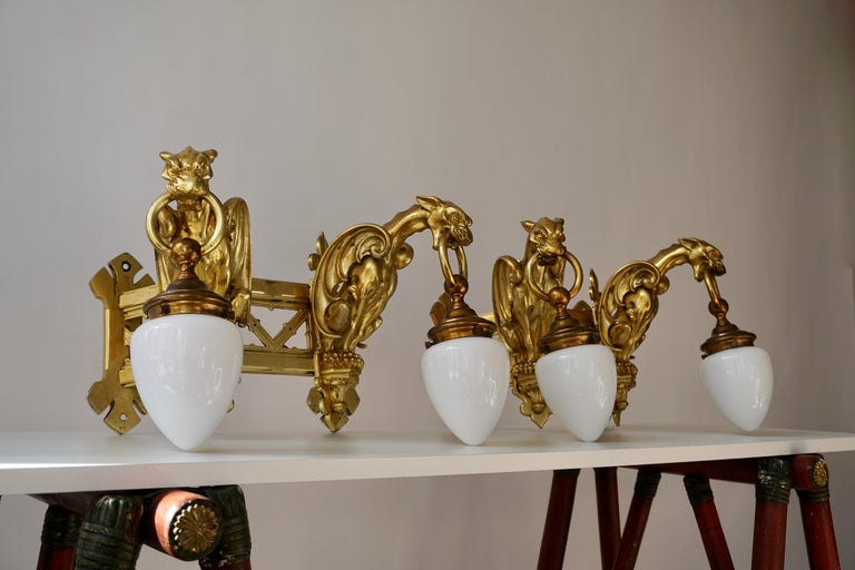 A pair of highly decorative wall-sconces in bronze guilt, representing two griffins, each carrying a lamp with a milk glass cover.
Italy, 20th century

Pair of bronze gilt wall Sconces representing two griffins
The wall light requires two single E27