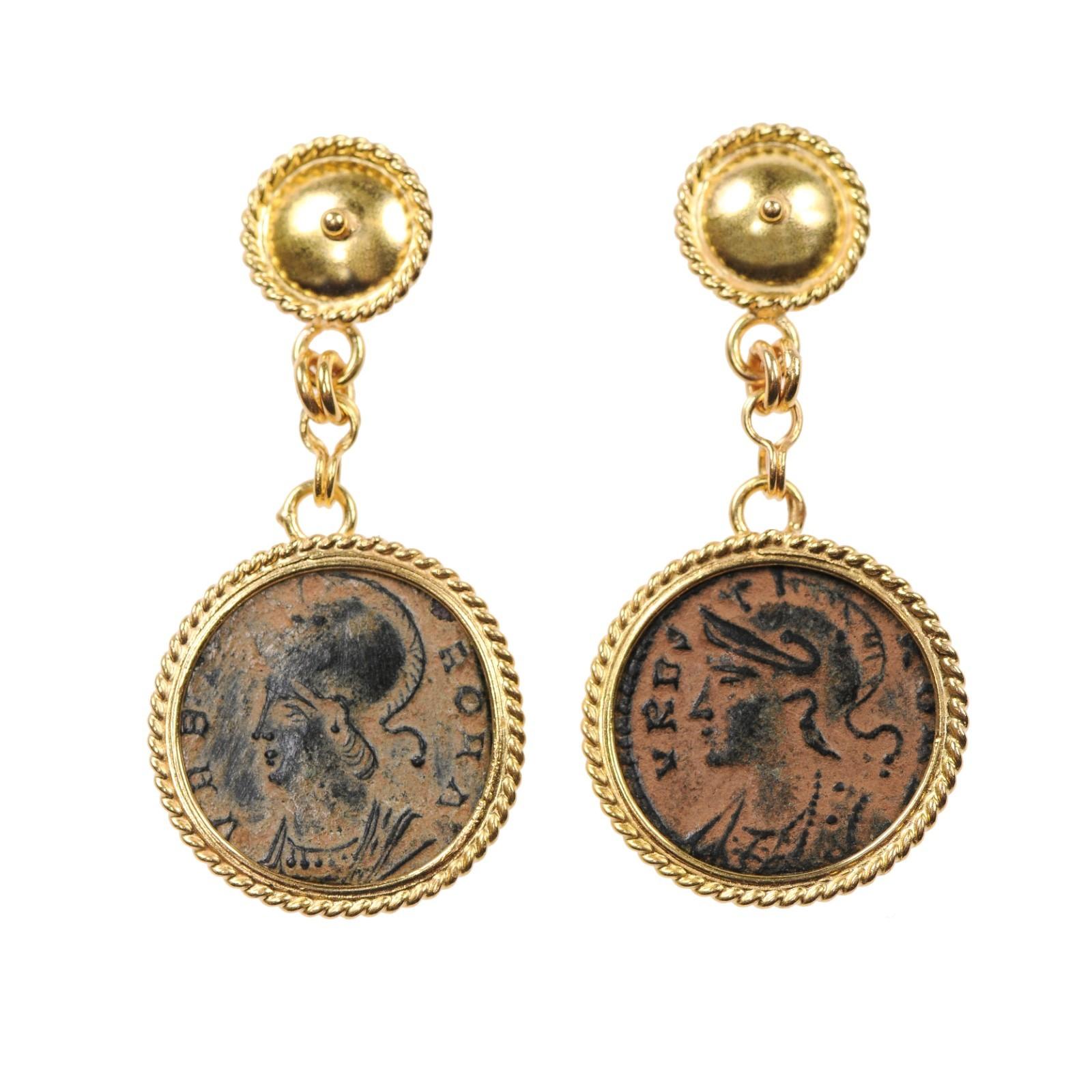 A pair of artisan created earrings from a pair of authentic bronze Hellenistic coins (circa 2nd century AD), which have each been set within 21 kt gold bezels with roped embellishment, dangling from round upper posts (with rope embellished surround)