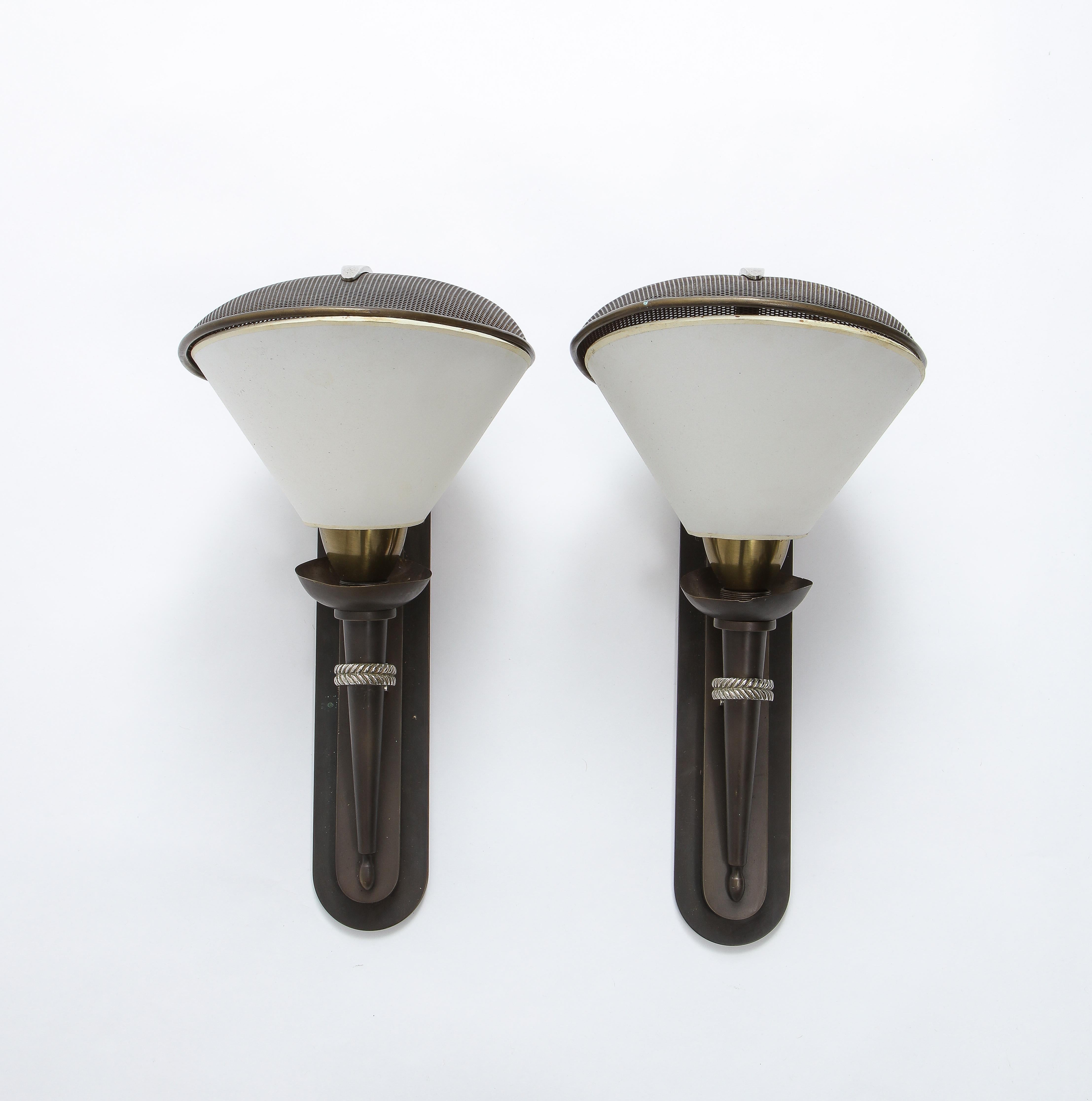 Elegant pair of sconces by Jansen, entirely made of bronze and finished in a rich brown patina with silver accents. These sconces are a classic example of French post-Art Deco design of the 1950s. The top is reminiscent of a fencing face mask, hence